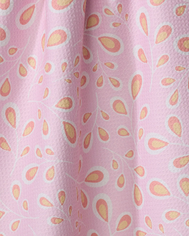 Close-up of the "Springtime Wonders" tea towel by Blissful Flamingo, featuring a textured pink surface and repeating white, yellow, and orange teardrop patterns. Made from recycled materials for an eco-friendly look.