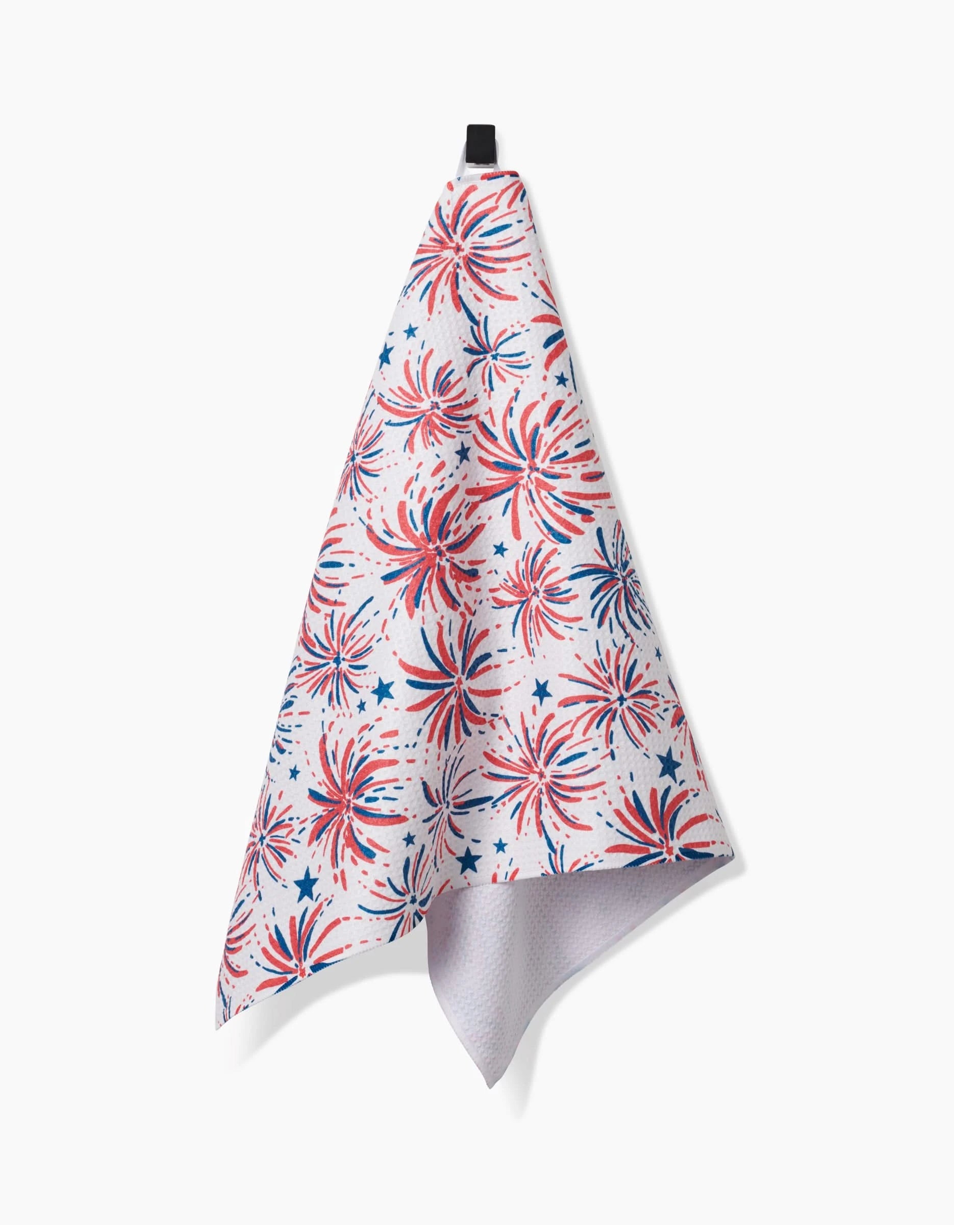 The Hufton Studio Stars And Fireworks white tea towel hangs from a black loop, featuring red, white, and blue fireworks and stars on Geoweave fabric for a festive patriotic touch.