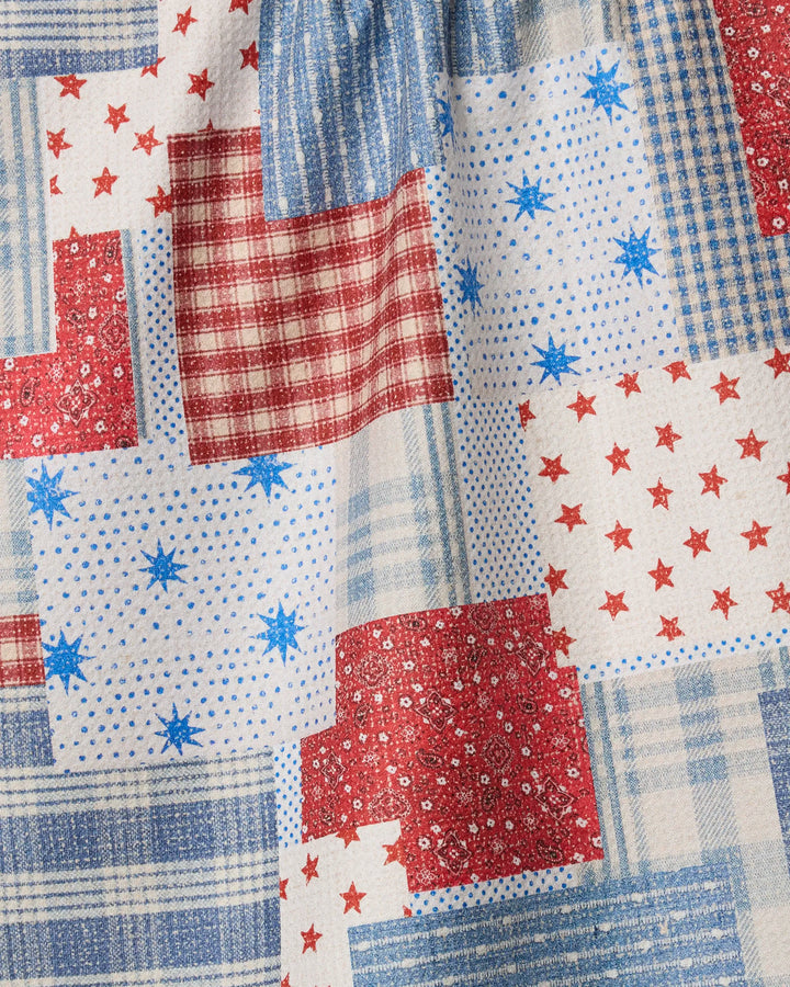 The Stars and Stitches quilt by Geometry features recycled kitchen towels crafted into red, white, and blue patchwork with stars, plaid, polka dots, and florals for a charming vintage Americana look.