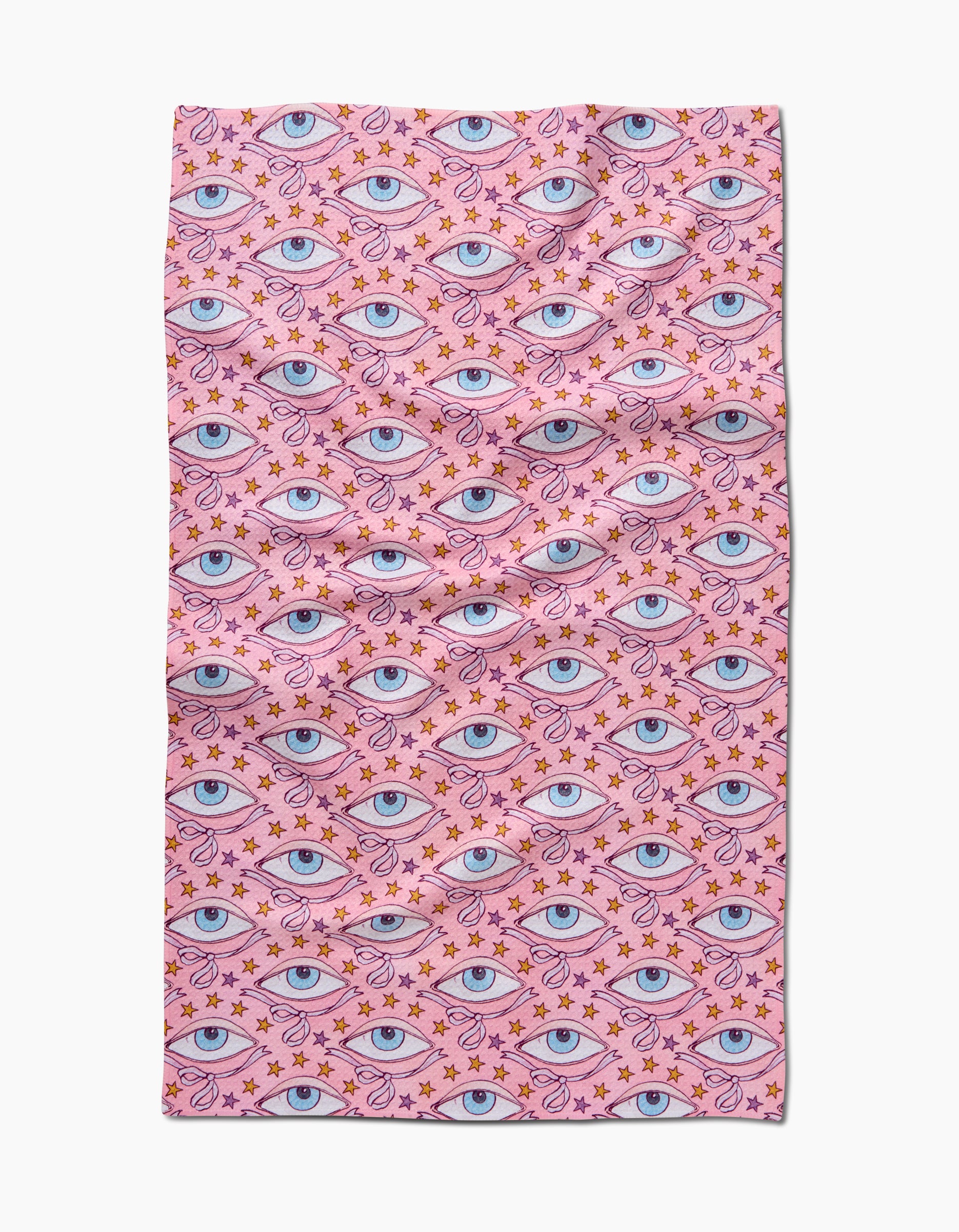 The Stella tea towel by Maayan Alper-Swan features pink Geoweave fabric with a repeating pattern of blue eyes, orange stars, and dots. Made from recycled materials, its slightly wrinkled look adds a whimsical, surreal touch.