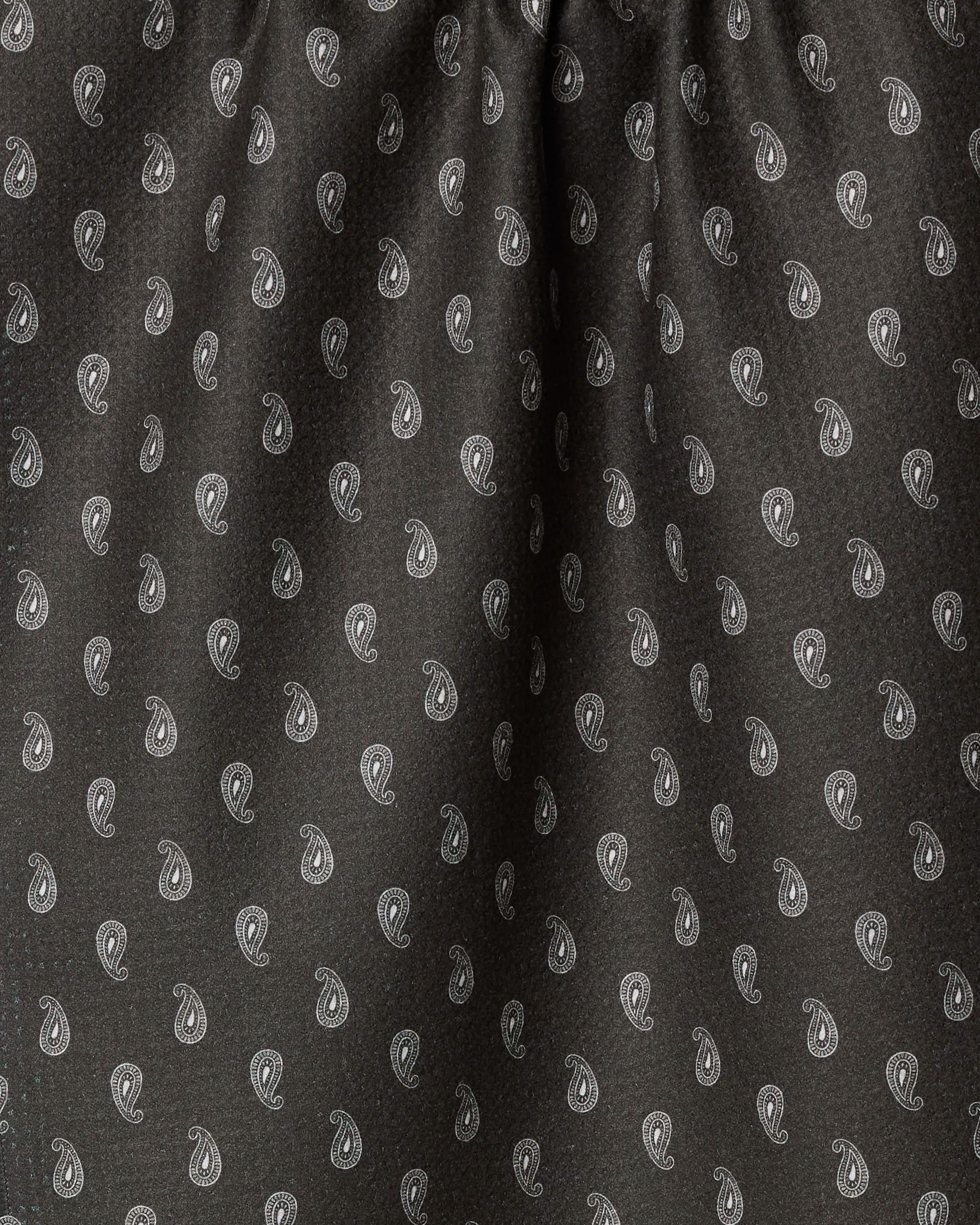 Close-up of Geometry's Stirrup Espresso tea towel, featuring a dark fabric with small white paisley designs evenly spaced across the surface and slight gathering at the top.