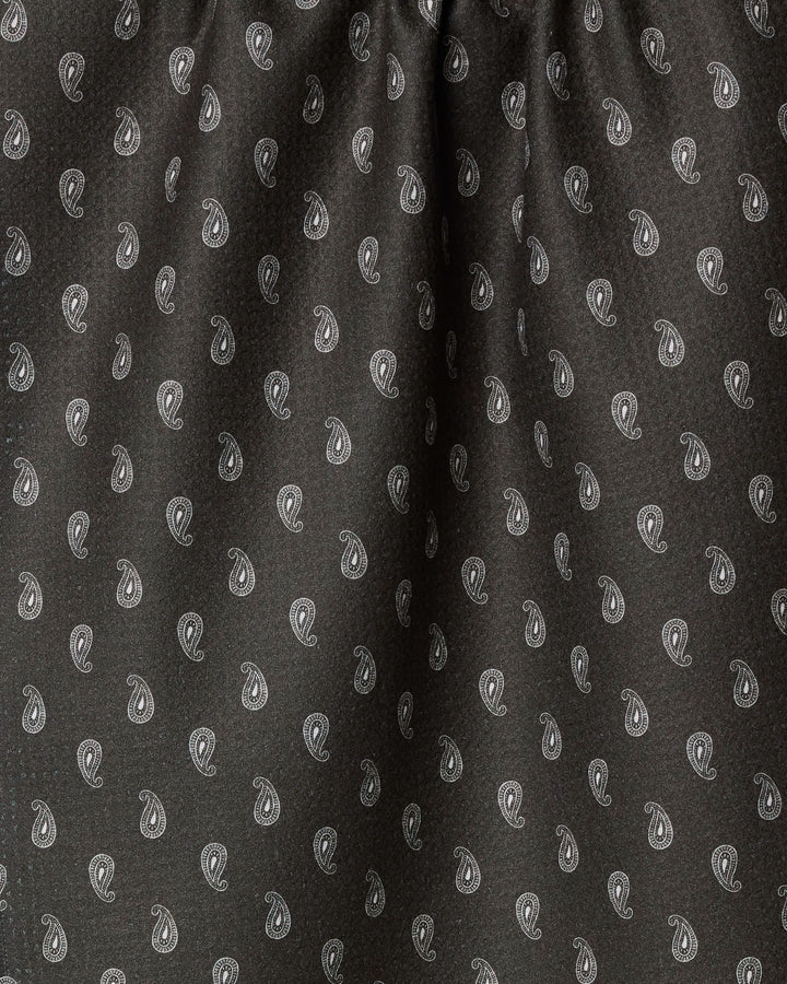 Close-up of Geometry's Stirrup Espresso tea towel, featuring a dark fabric with small white paisley designs evenly spaced across the surface and slight gathering at the top.