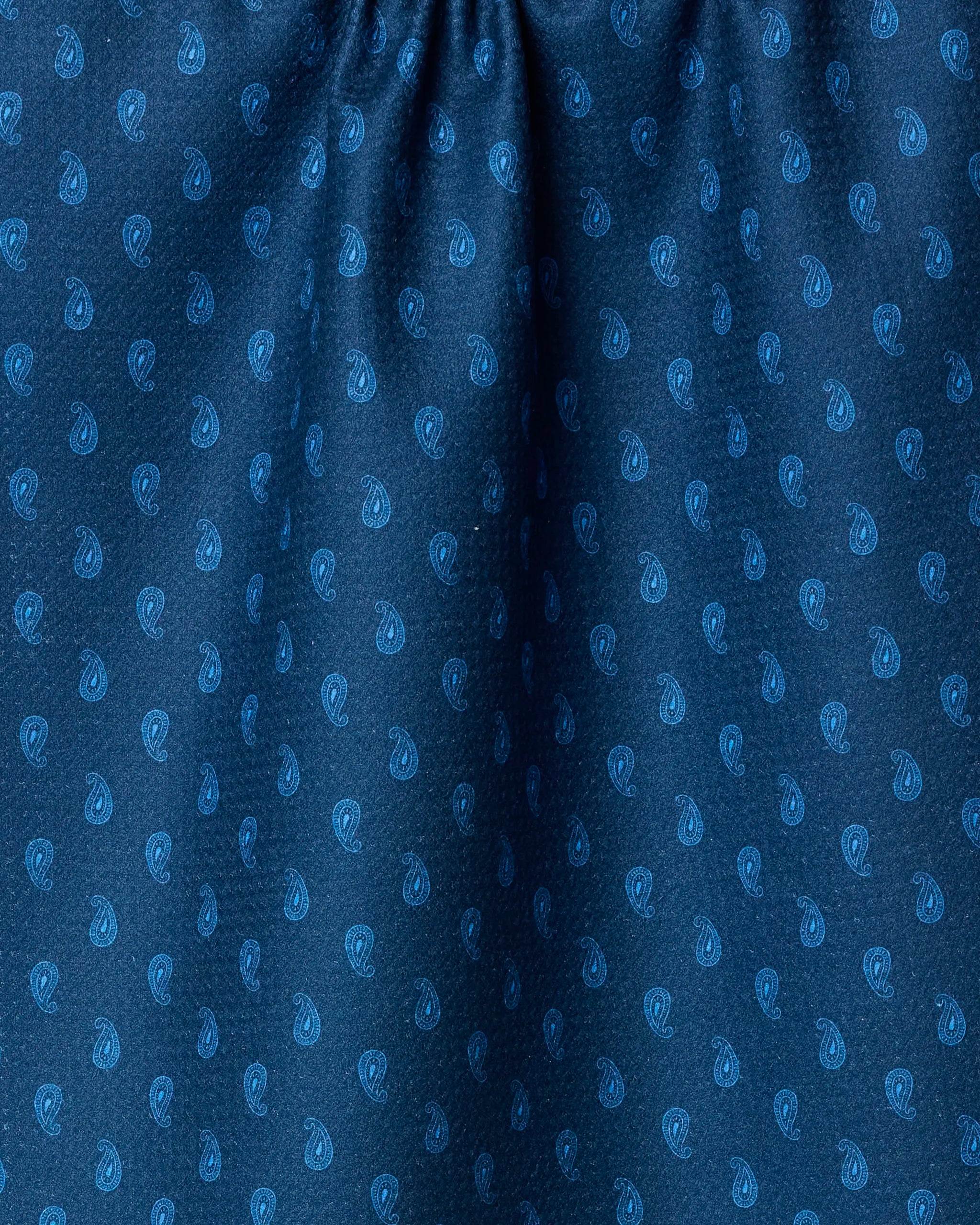 Close-up of Geometry’s Stirrup Indigo: blue fabric made from recycled materials, featuring a lighter blue repeating paisley pattern with subtle folds and gathered texture at the top.