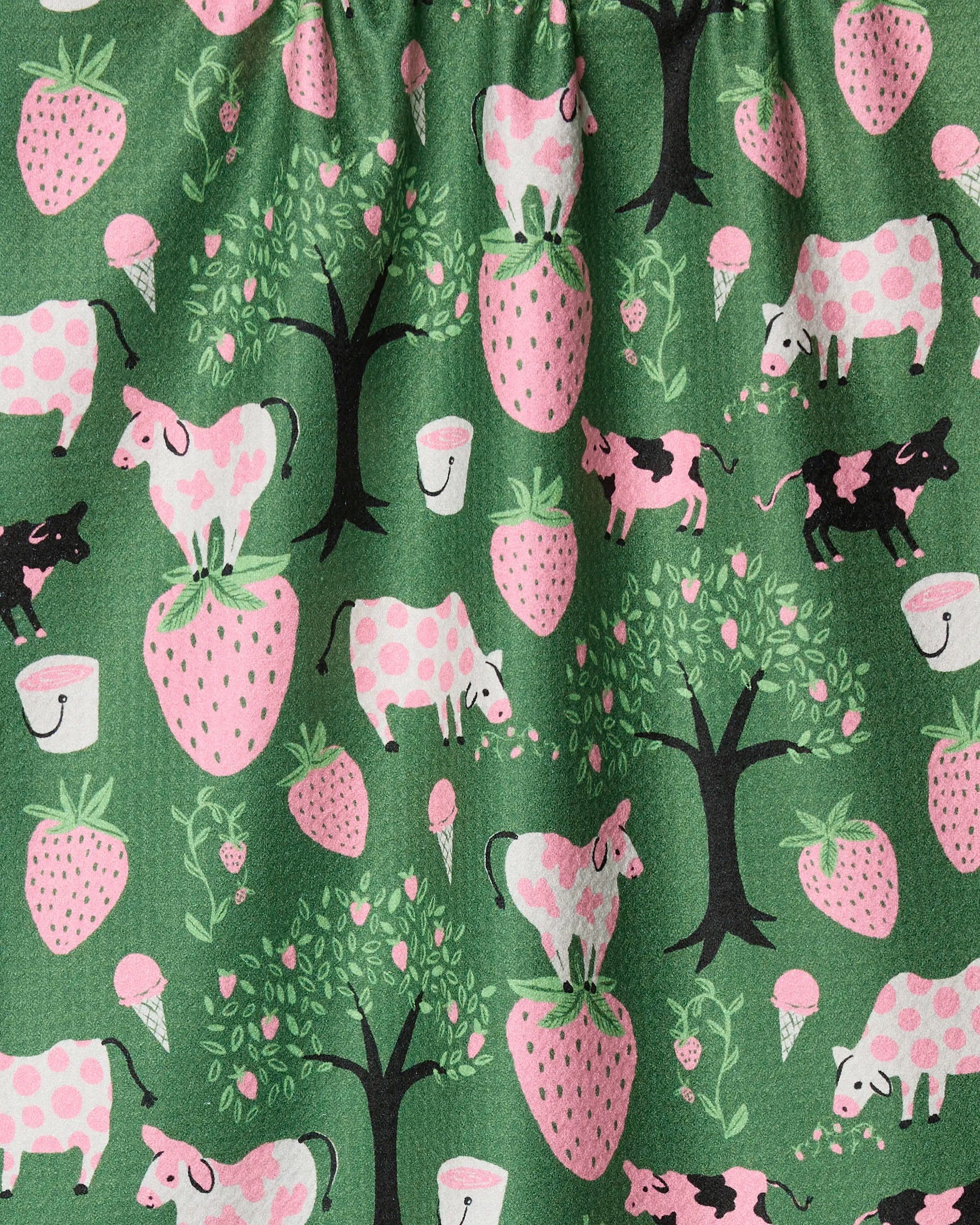 The Strawberry Cows dish towel by Louise Pretzel features a green fabric with whimsical pink and black cows, strawberries, trees, milk buckets, and ice cream cones—an ultra-absorbent kitchen accessory with charming strawberry-spotted cows.