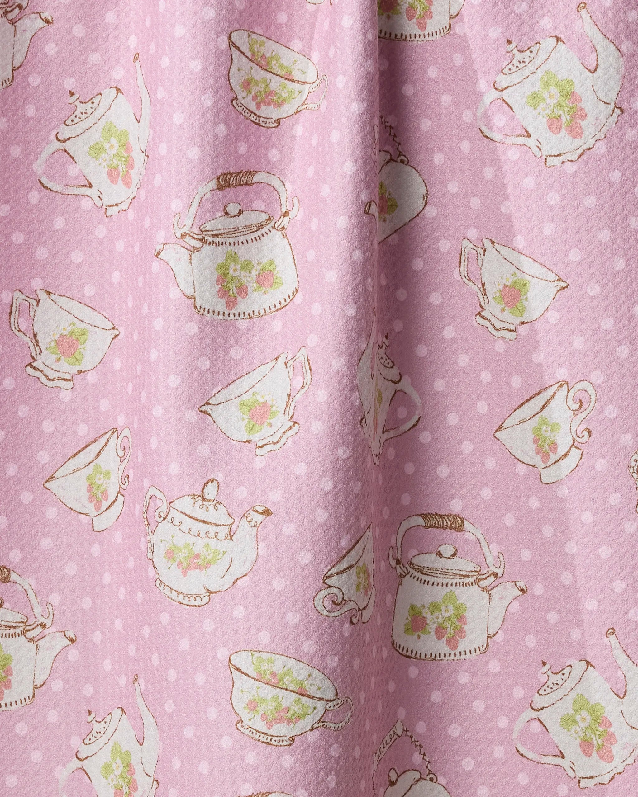 Strawberry Tea by Geometry features pink fabric with white polka dots and vintage teapots, teacups, and saucers adorned with green leaves and pink roses—ideal for a charming kitchen towel.