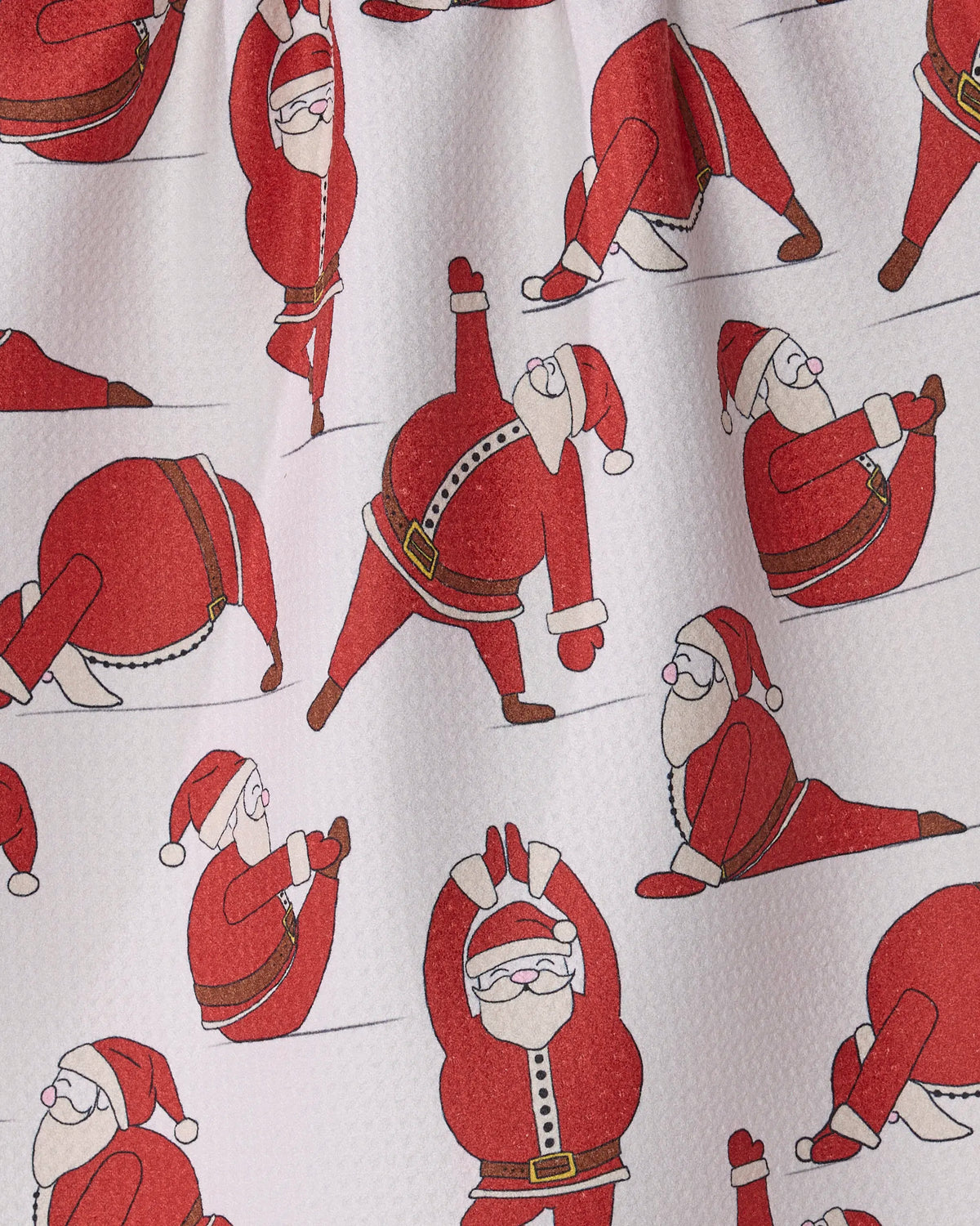 Stretchy Santy by Geometry features cartoon Santas in red suits and hats striking various yoga poses on a white, textured background, making this eco-friendly tea towel a cheerful and practical addition to your holiday kitchen décor.