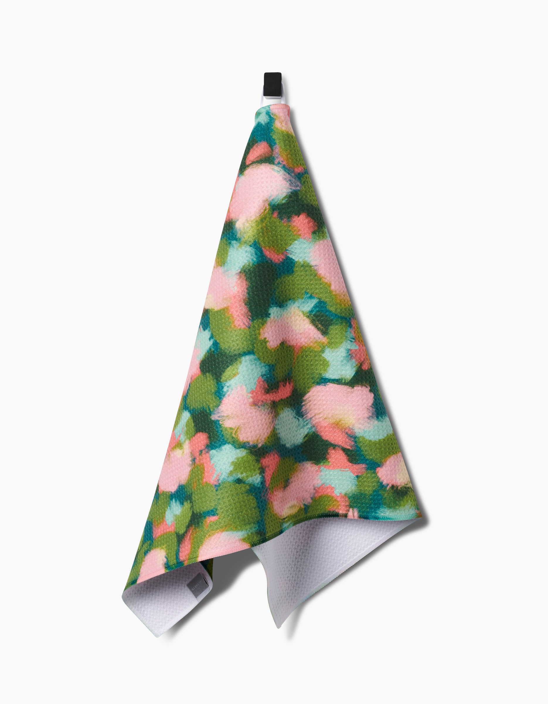 The Shelley Smith Stroke of Genius dish towel features a colorful abstract floral pattern in pink, green, and blue, hangs from a black loop, and is made with ultra-absorbent Geoweave fabric for superior performance.