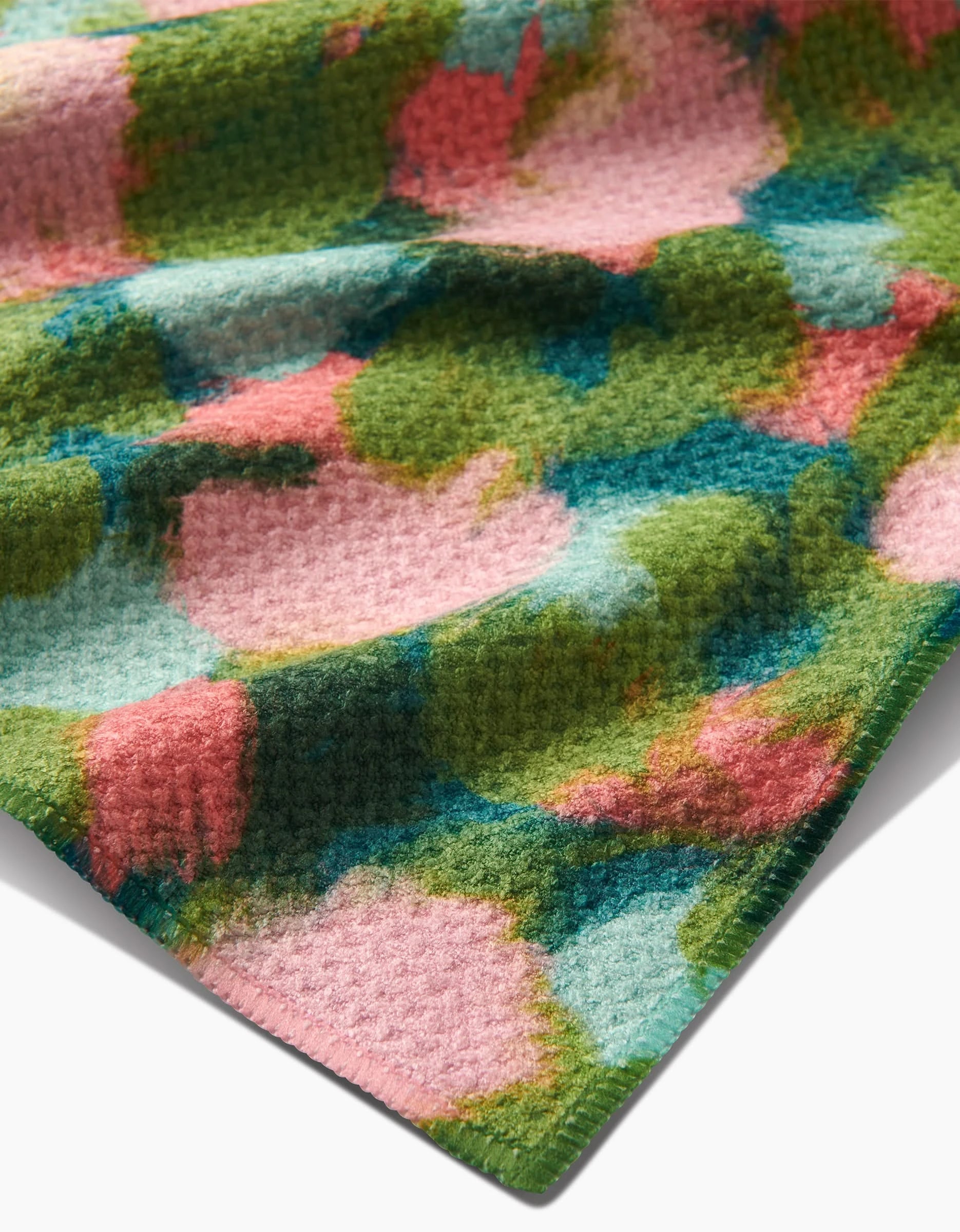A close-up of Shelley Smith’s Stroke of Genius Geoweave fabric, showcasing its colorful green, pink, and blue abstract pattern with soft shapes and a slightly raised, ultra-absorbent waffle-like surface.