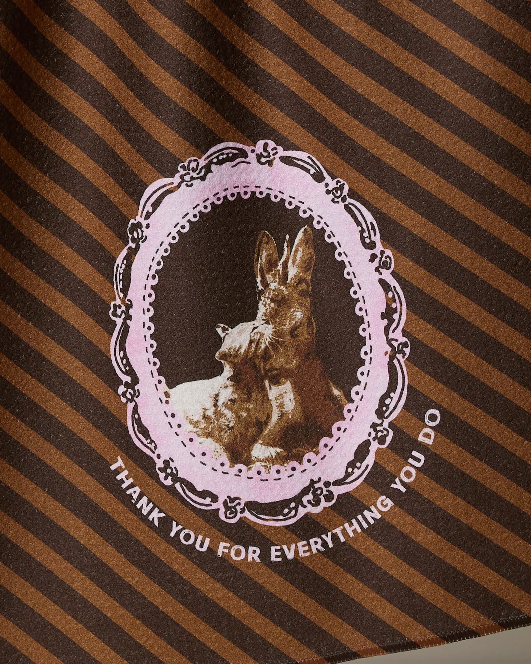 The Geometry "Strong and Caring" kitchen tea towel features brown stripes, a pink ornate oval frame with two kangaroos, and “THANK YOU FOR EVERYTHING YOU DO” in white text. Made from recycled materials.