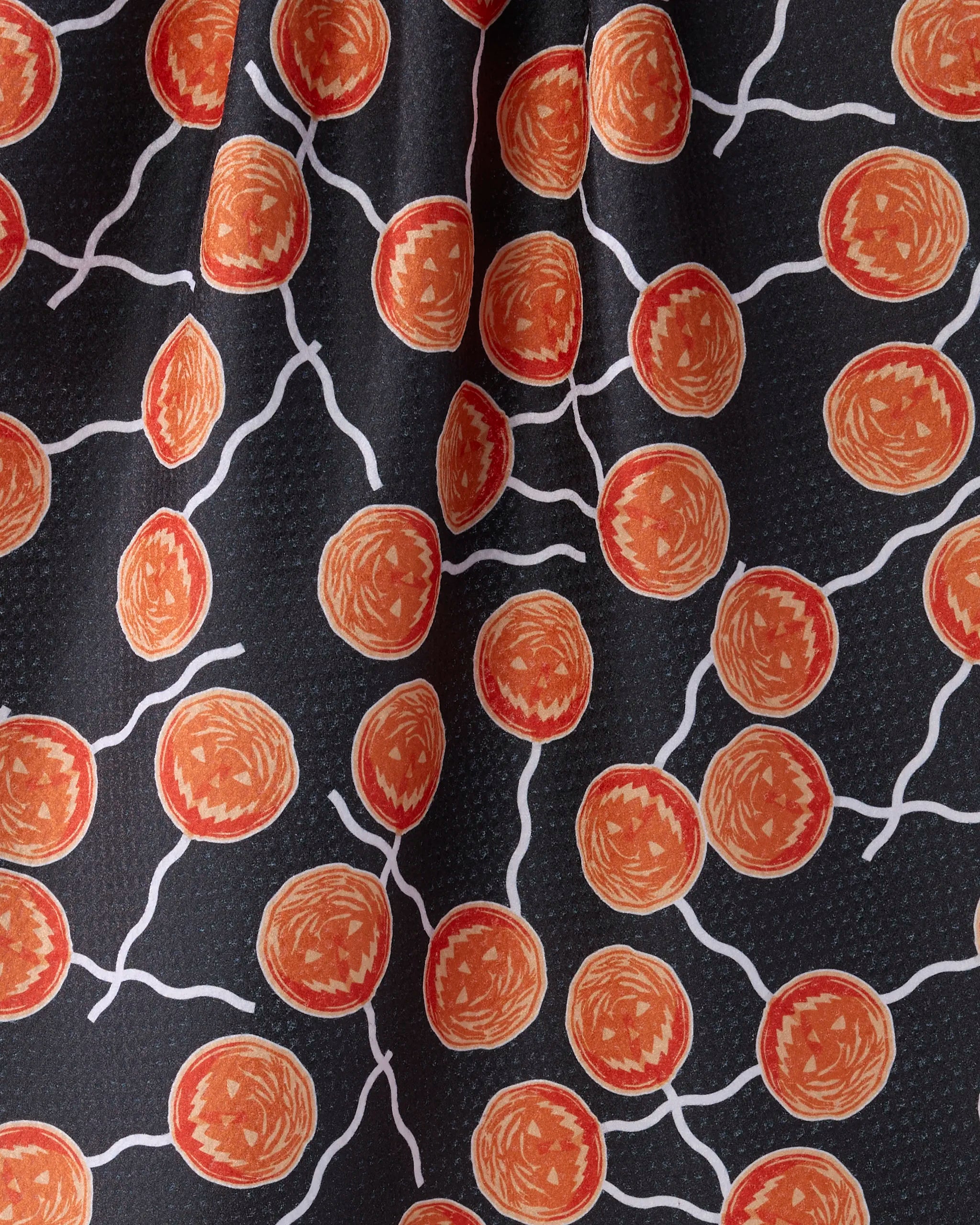 Geometry’s "Sugar Shock" tea towel features orange and red circular shapes linked by wavy white lines on a black background, resembling stylized cells. Subtle fabric texture and slight folds add detail to this quick-drying kitchen essential.