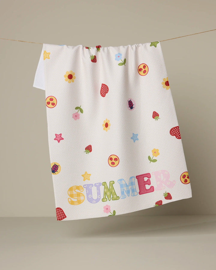 The Geometry “Summer Alphabet” tea towel features colorful flowers, strawberries, smiley faces, stars, and bold multicolored SUMMER text. This ultra-absorbent white towel brings cheerful vibes to your kitchen.