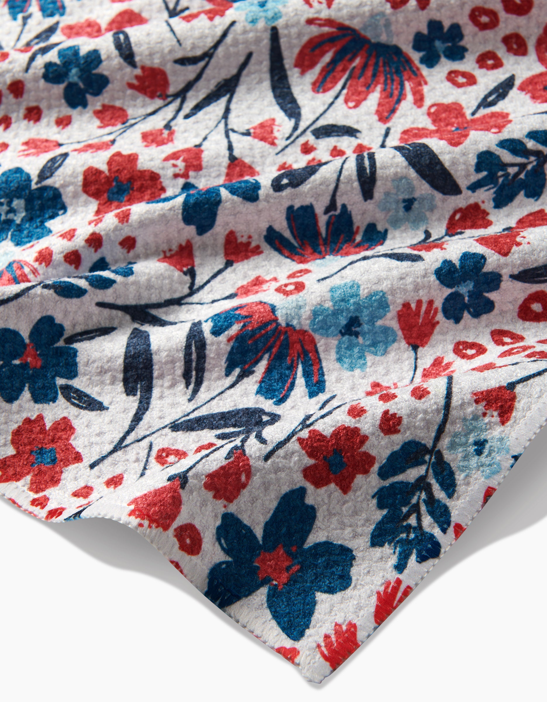 The Summer Bloom tea towel by Hufton Studio features a soft gray Geoweave fabric with a vibrant red, blue, and black floral pattern of flowers and leaves shown in close-up detail.