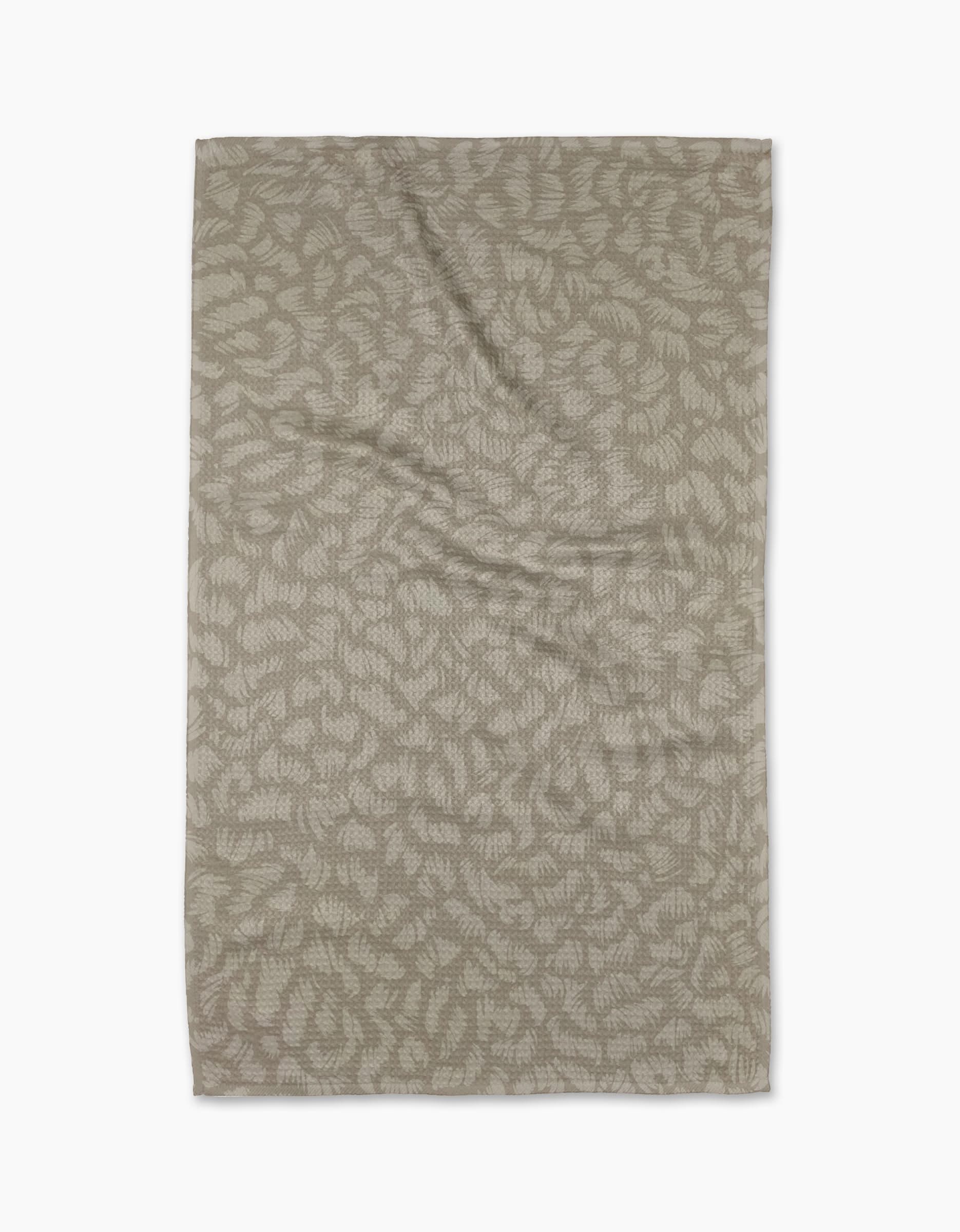 A rectangular, beige Sun Kissed tea towel by Geometry, crafted from eco-friendly Geoweave fabric with an abstract leaf pattern, is laid flat on a white background.