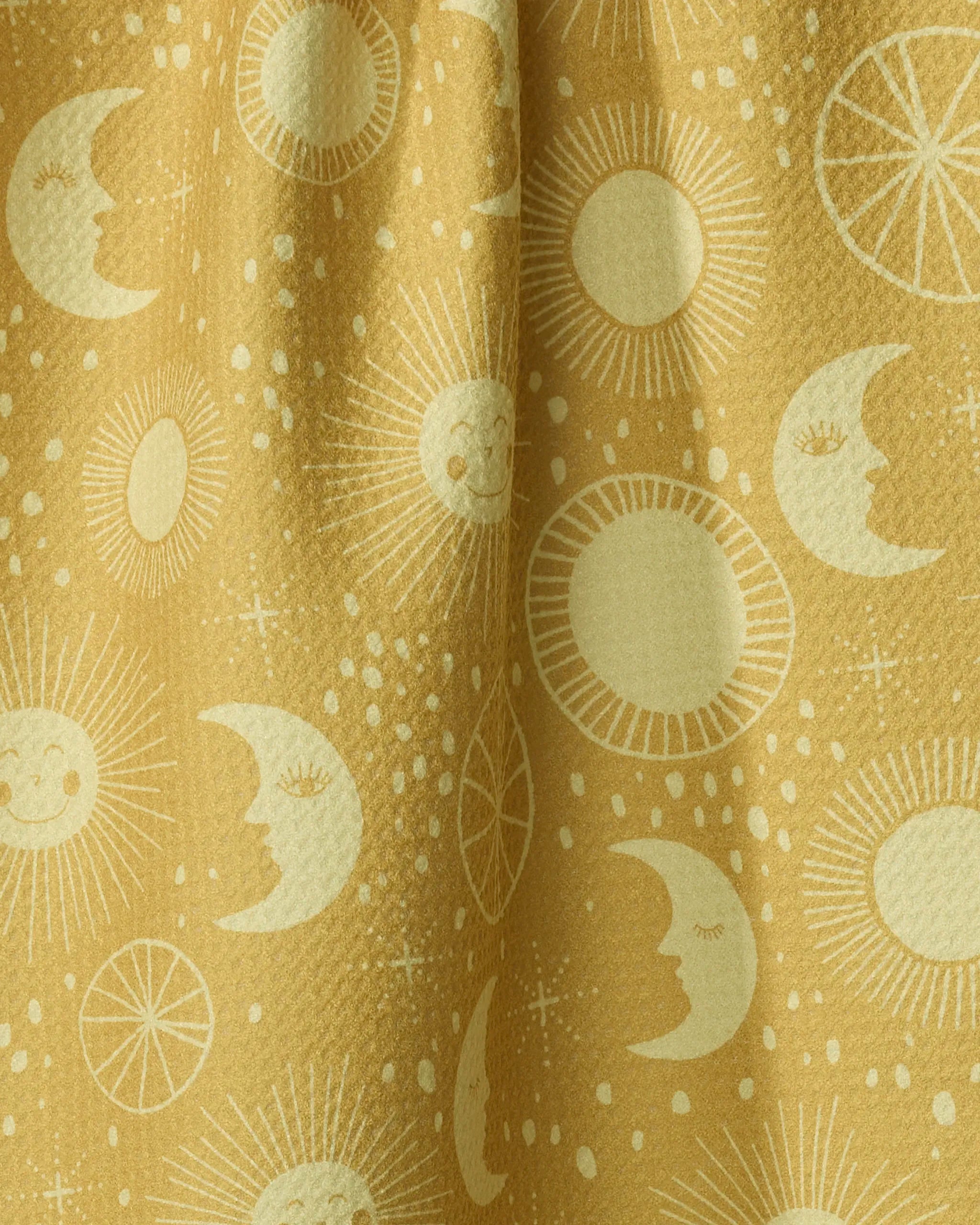 The Sun Moon Star tea towel by Jessica Swift features yellow fabric with whimsical, smiling sun, moon, and star patterns. Made from recycled materials for an eco-friendly touch.
