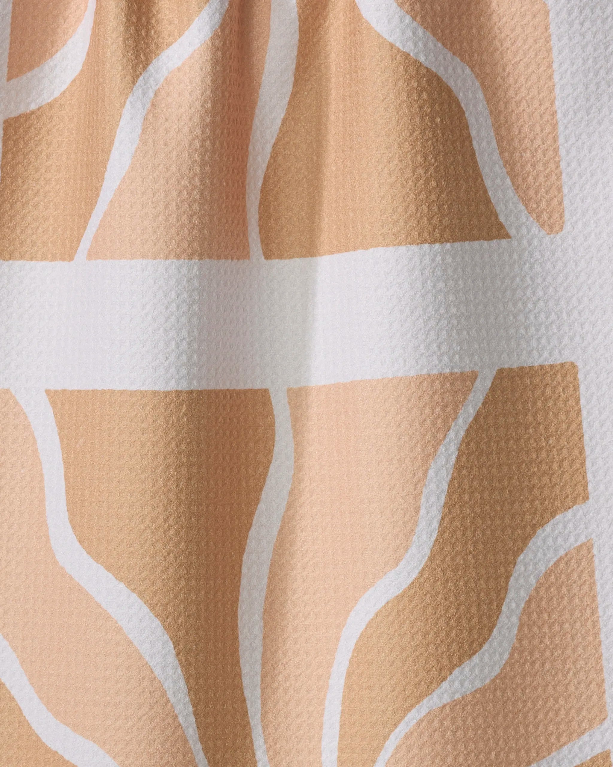 Close-up of the "Sun Rays" tea towel by Graphics and Grain—features wavy beige and white abstract lines over a peach background, creating organic shapes. Made from recycled materials.