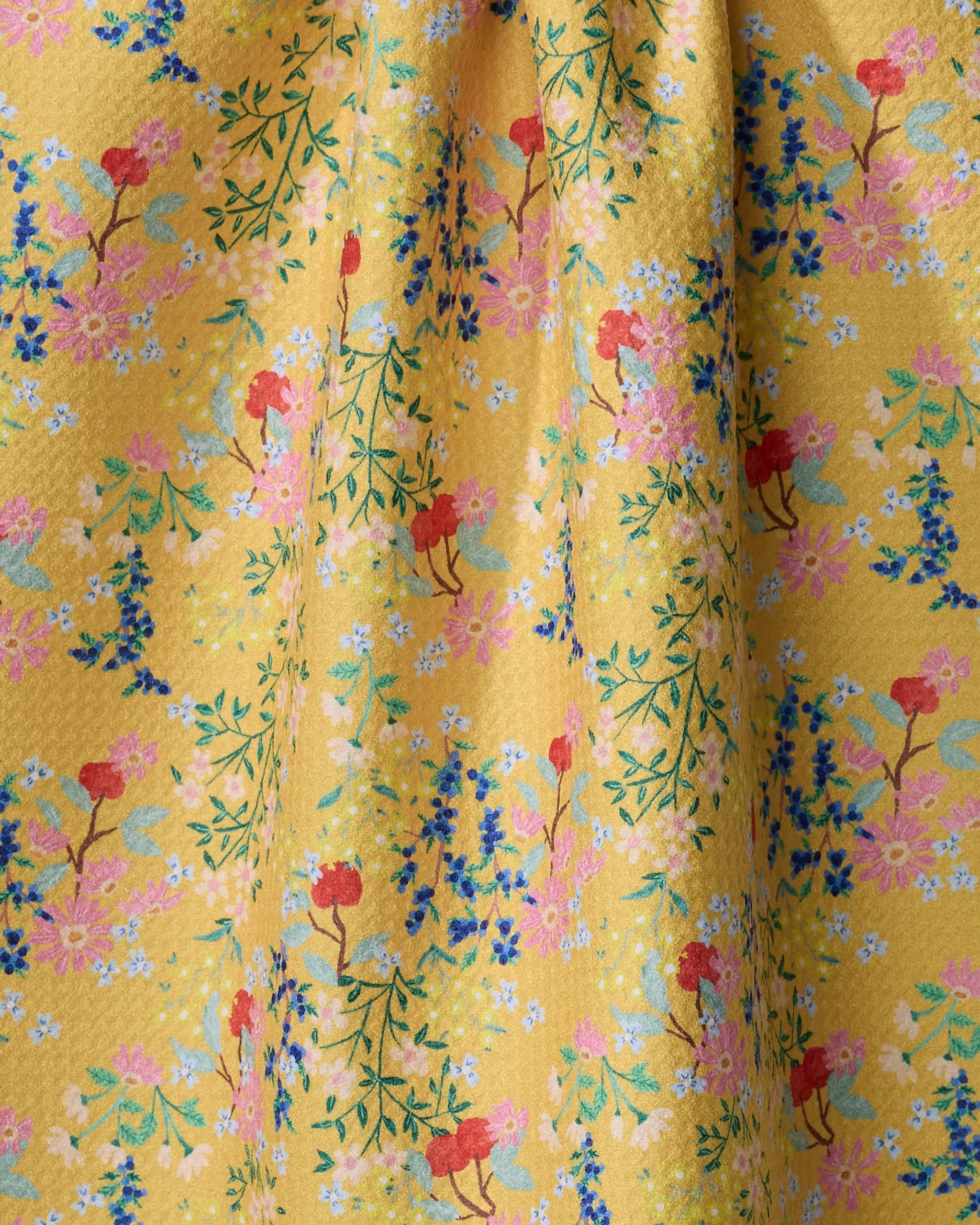 The Sunny Cherry Blossoms tea towel by Brittany Jepsen features soft yellow fabric with red, pink, blue, and white floral patterns plus green leaves, adding both beauty and practicality to any kitchen.