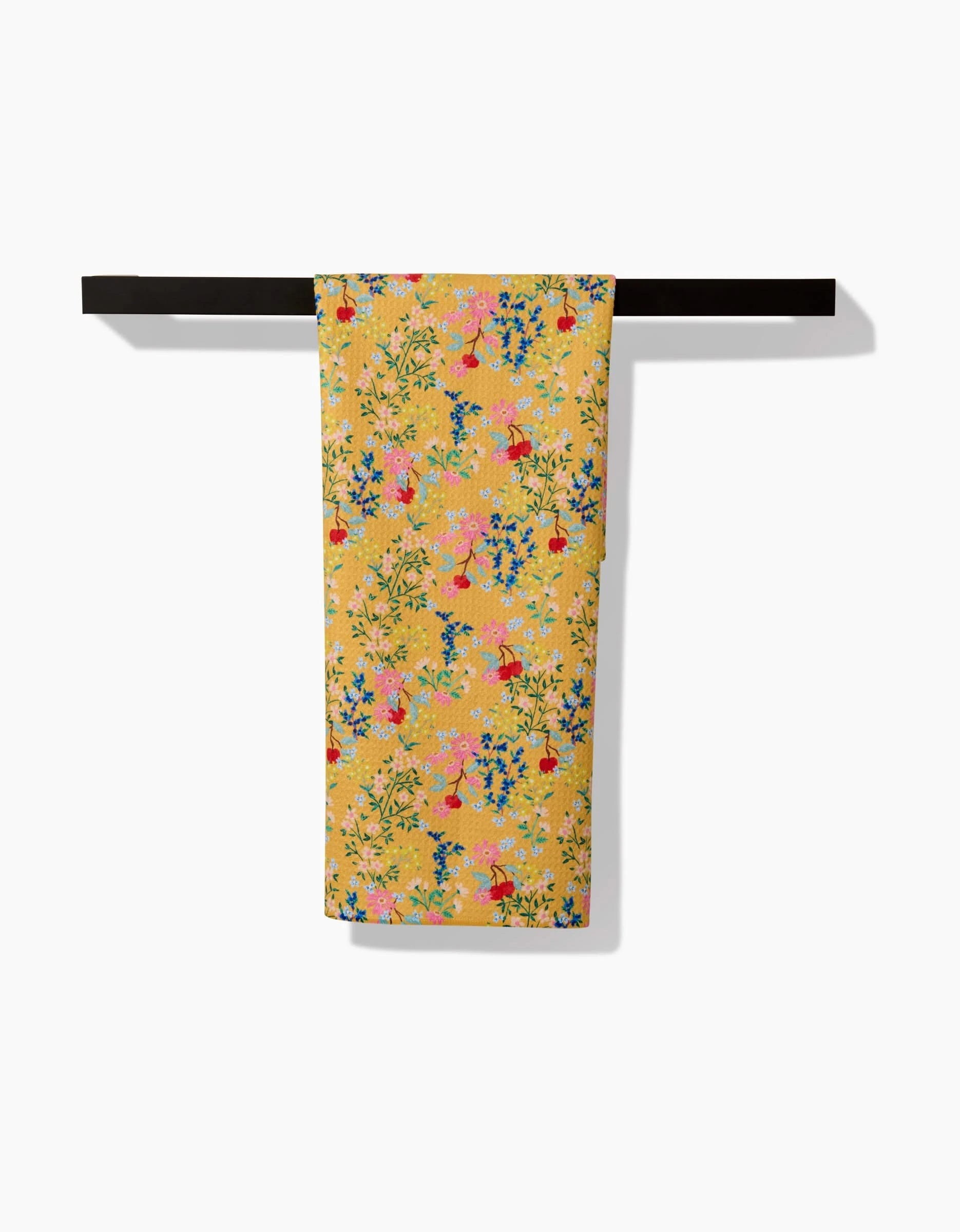 The Sunny Cherry Blossoms tea towel by Brittany Jepsen, featuring a vibrant floral yellow Geoweave™ design, is draped over a black rod against a white background.