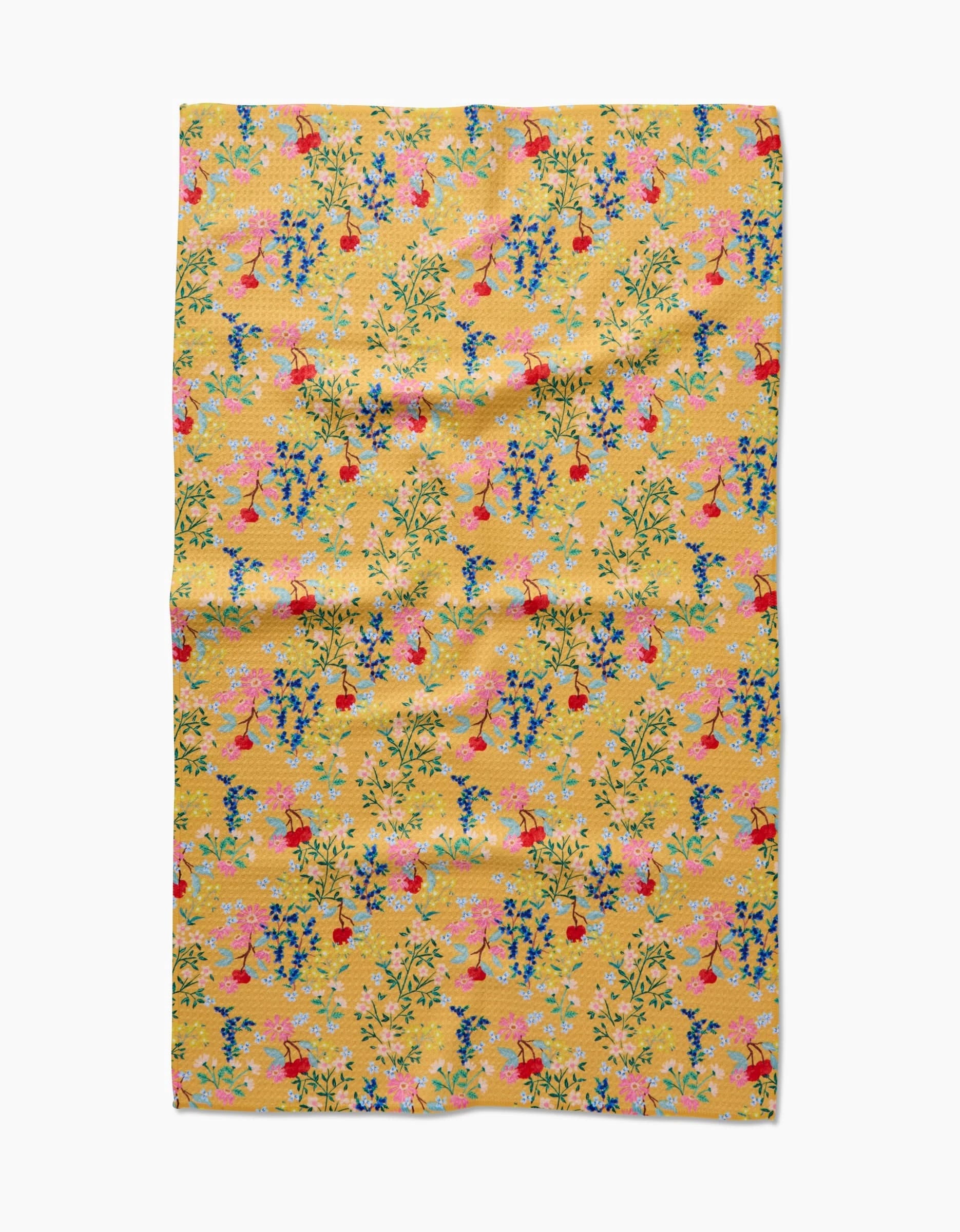 The Sunny Cherry Blossoms tea towel by Brittany Jepsen is a yellow rectangular towel with a vibrant floral and red bird pattern on green leafy branches. Made from recycled materials, the fabric has a slightly wrinkled look.
