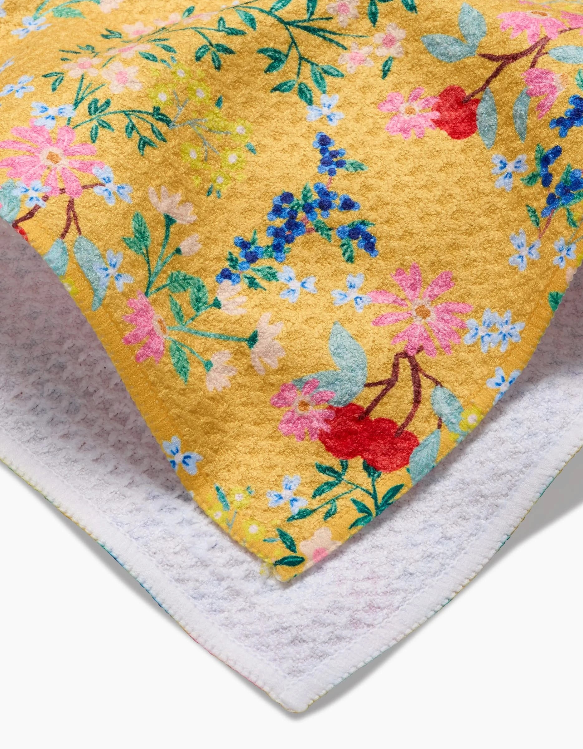 A close-up of the Brittany Jepsen Sunny Cherry Blossoms tea towel shows a yellow, floral Geoweave™ top and a white, textured underside for superior absorbency.