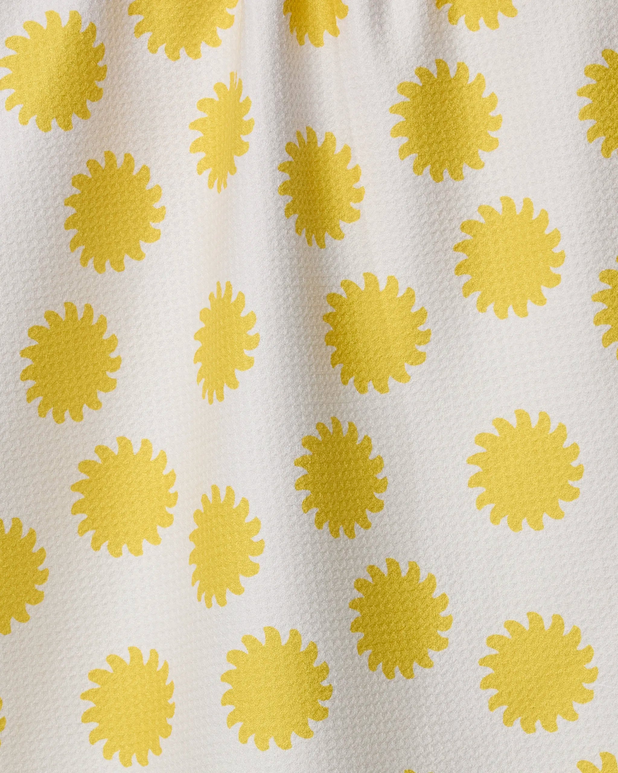 The "Sunny Side" towel by Geometry features ultra-absorbent white fabric with a textured surface and an even pattern of bright yellow, stylized sunburst shapes.