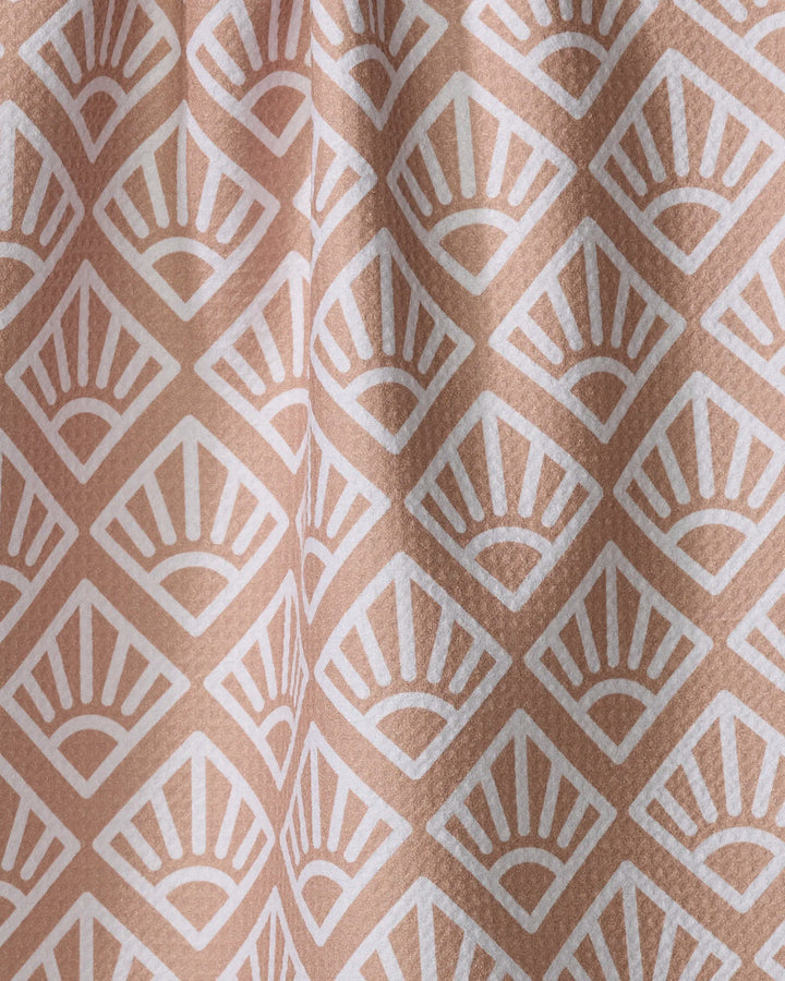 Sunrise Mosaic by Rosa Kichline features beige fabric with a repeating white art deco fan pattern in diamond shapes. Its slightly folded texture makes this absorbent tea towel a charming and functional addition to any kitchen.