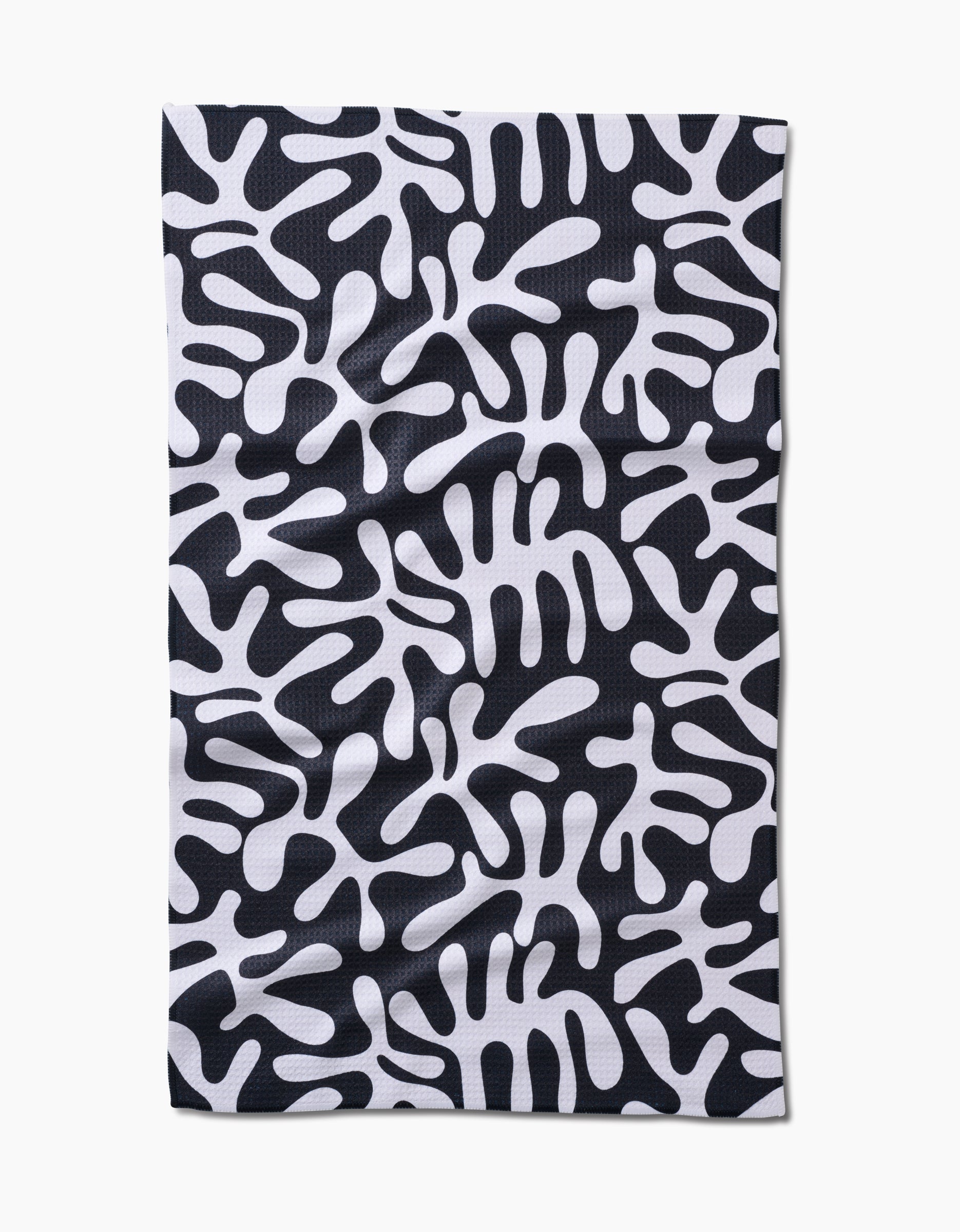 The Sunset tea towel by Marina Solodka features a rectangular, ultra-absorbent Geoweave™ fabric with a black background and abstract white, amoeba-like patterns.