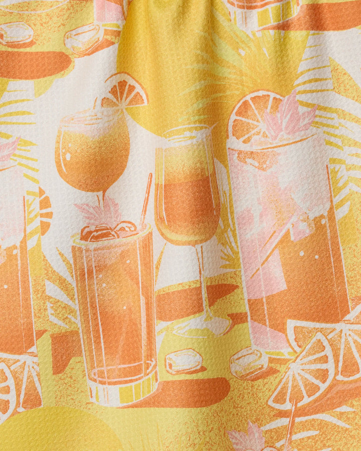 The Geometry "Sunset Happy Hour" dish towel features a vibrant pattern of tropical cocktails, ice cubes, citrus slices in orange, yellow, and pink hues, and leafy backgrounds—perfect for brightening your kitchen.