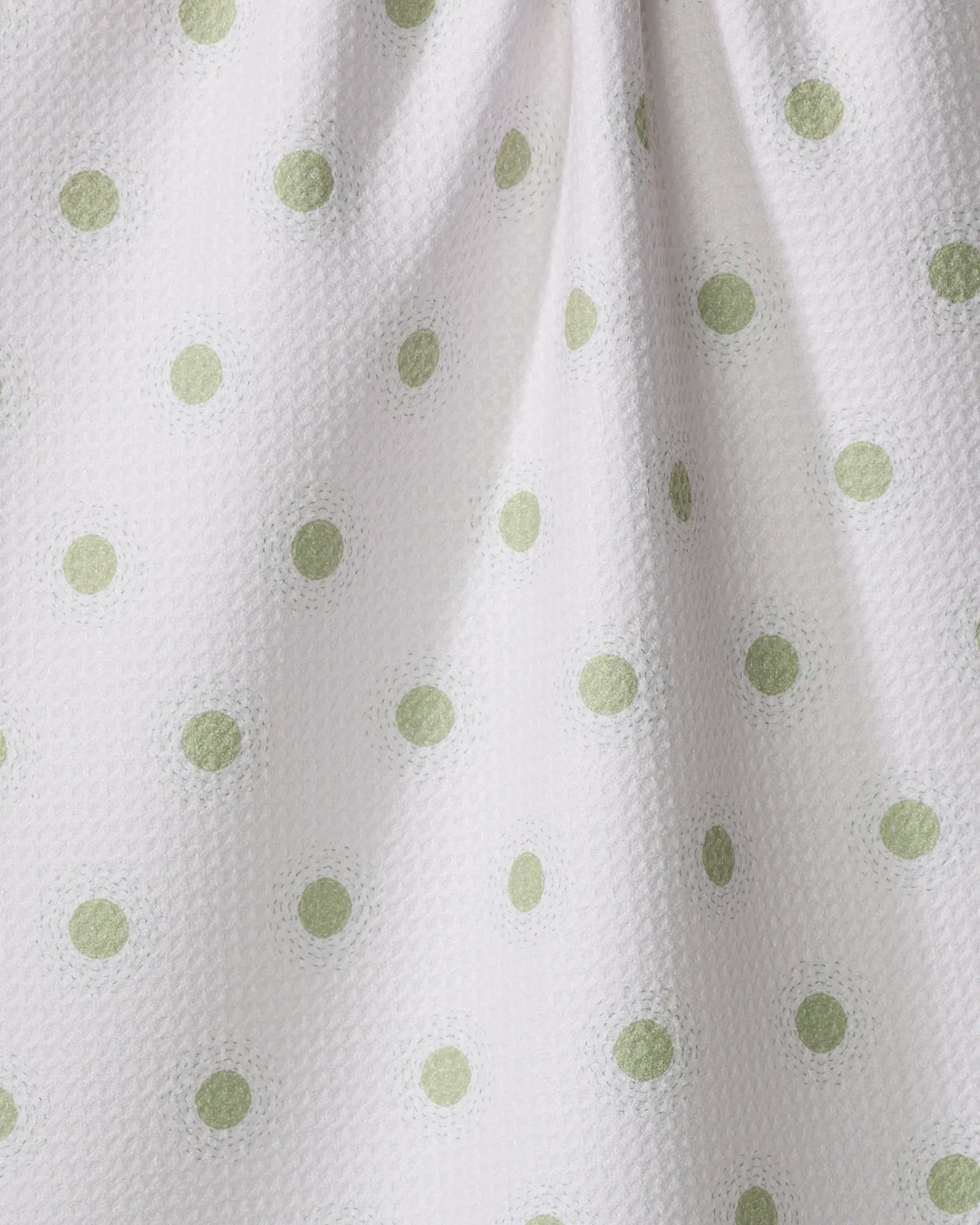 Close-up of Sunshine Glow by Danelys Sidron—a white, eco-friendly tea towel with light green polka dots and a softly dimpled texture, ideal as an absorbent kitchen dish towel.
