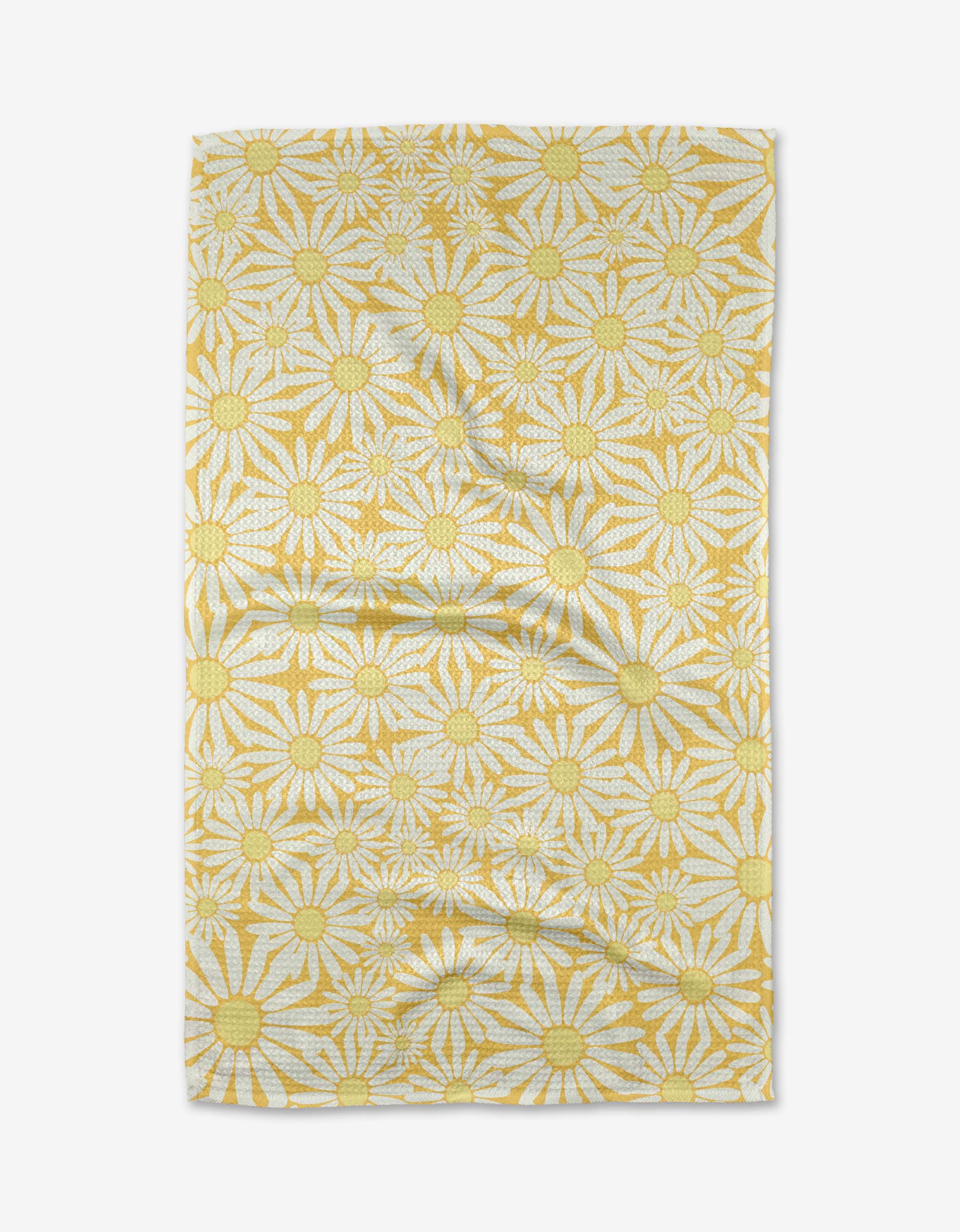 The Rebecca Bobko Sunshine Meadow rectangular cloth, made from ultra-absorbent Geoweave fabric, features yellow and white daisies with large yellow centers on a white background and is shown slightly wrinkled on a white surface.
