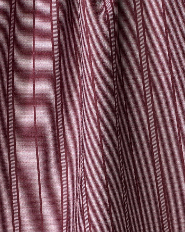 Close-up of Super Stripe - Wine by The Buy Guide, a pleated kitchen towel featuring vertical maroon stripes on muted mauve. Made from recycled materials, its soft folds and subtle light variations add elegant texture.
