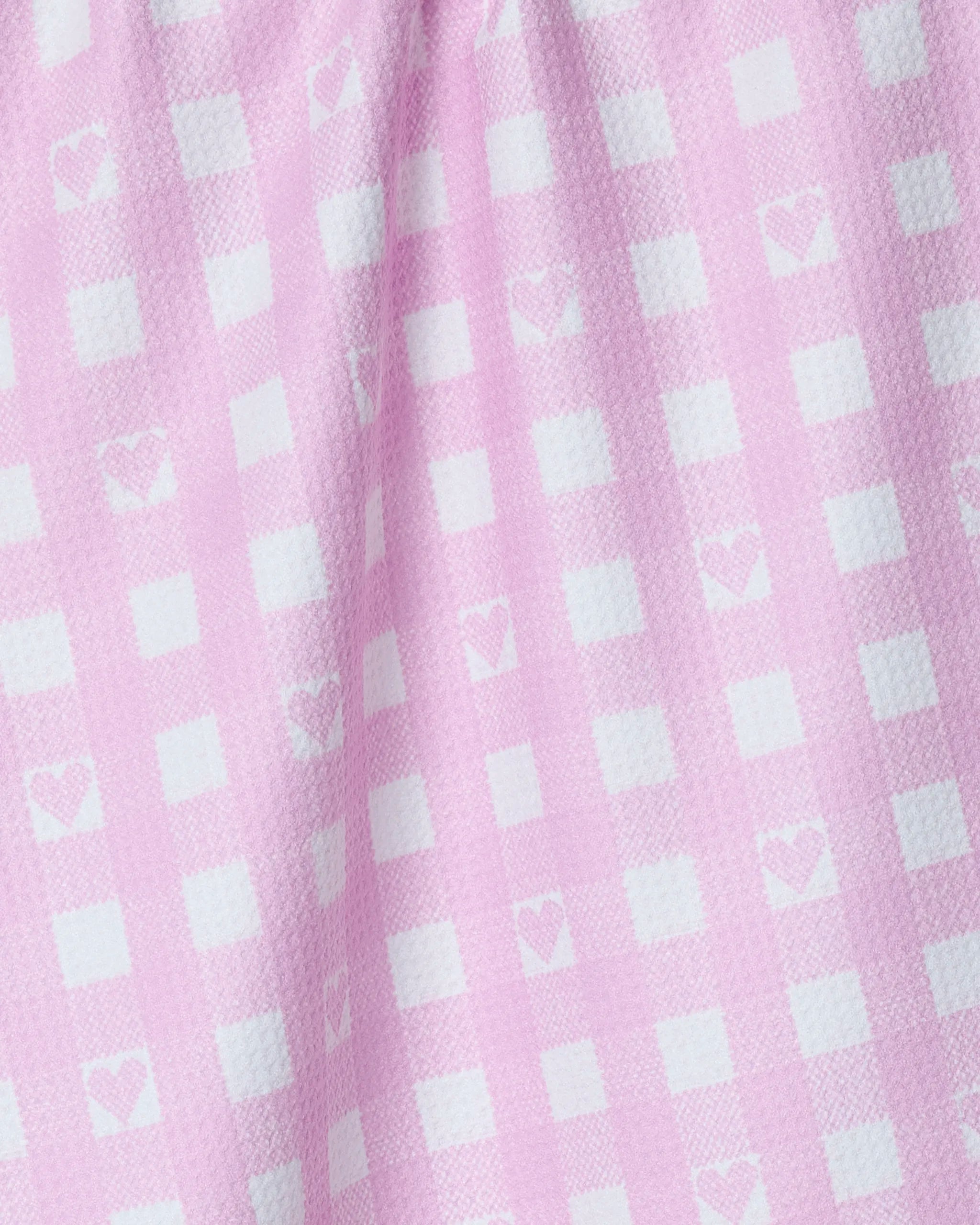 Close-up of Geometry’s Super Sweet Check eco-friendly kitchen towel featuring pink and white gingham with small white hearts. Soft, textured, and gently folded, it brings a charming touch to any kitchen space.