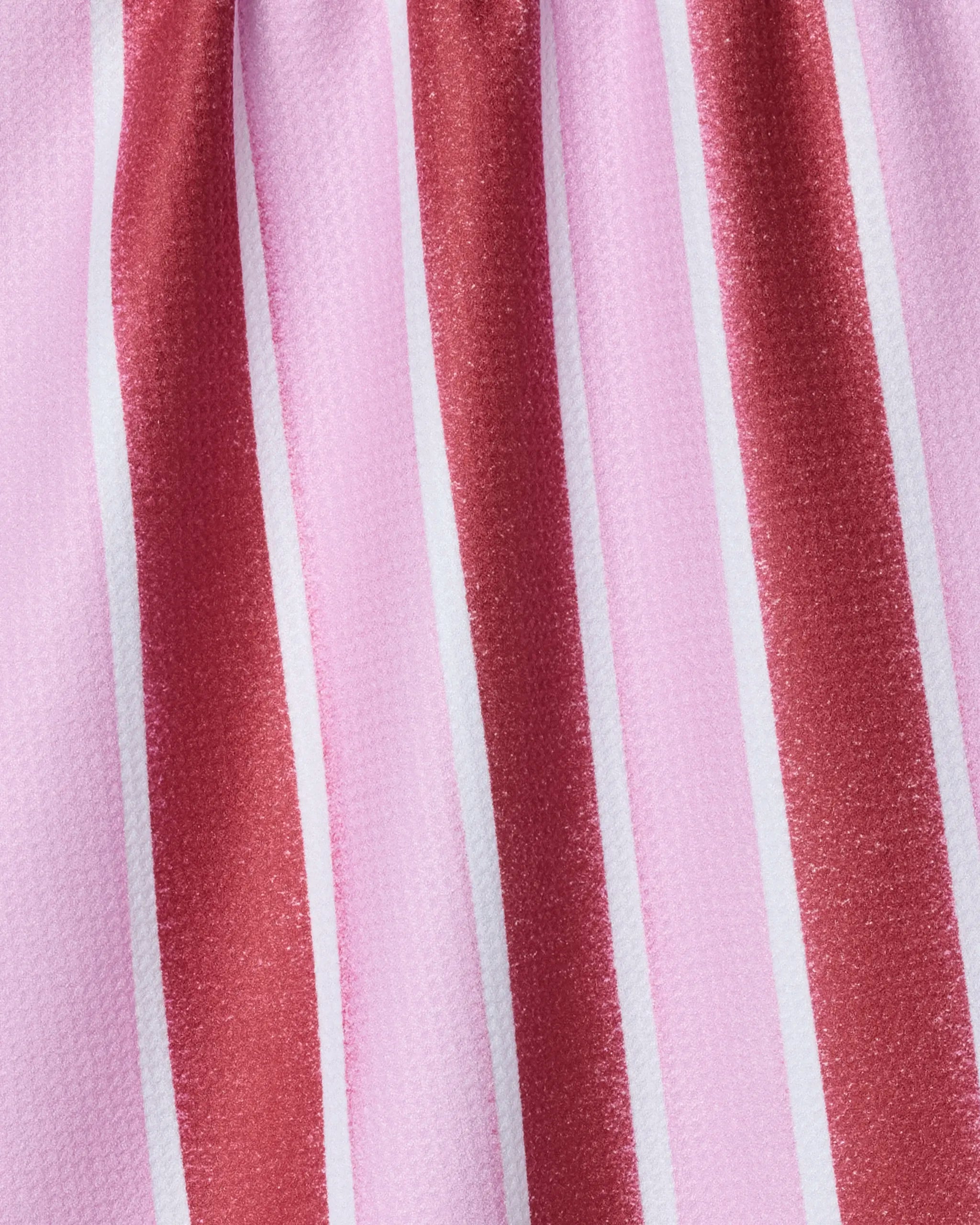 Close-up of Geometry's Super Sweet Stripe recycled kitchen towel, featuring vertical stripes in pink, white, and red with a slightly glossy texture and gentle vertical folds.