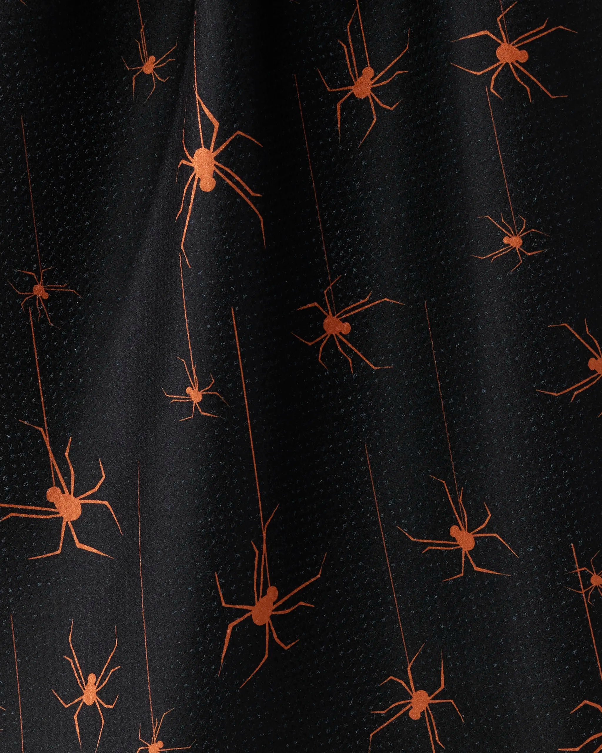 Suspended" by Geometry features black fabric with an orange spider pattern. Varied spiders and fine lines evoke dynamic webs, while its slight texture ensures the tea towel is both striking and quick-drying for your kitchen.