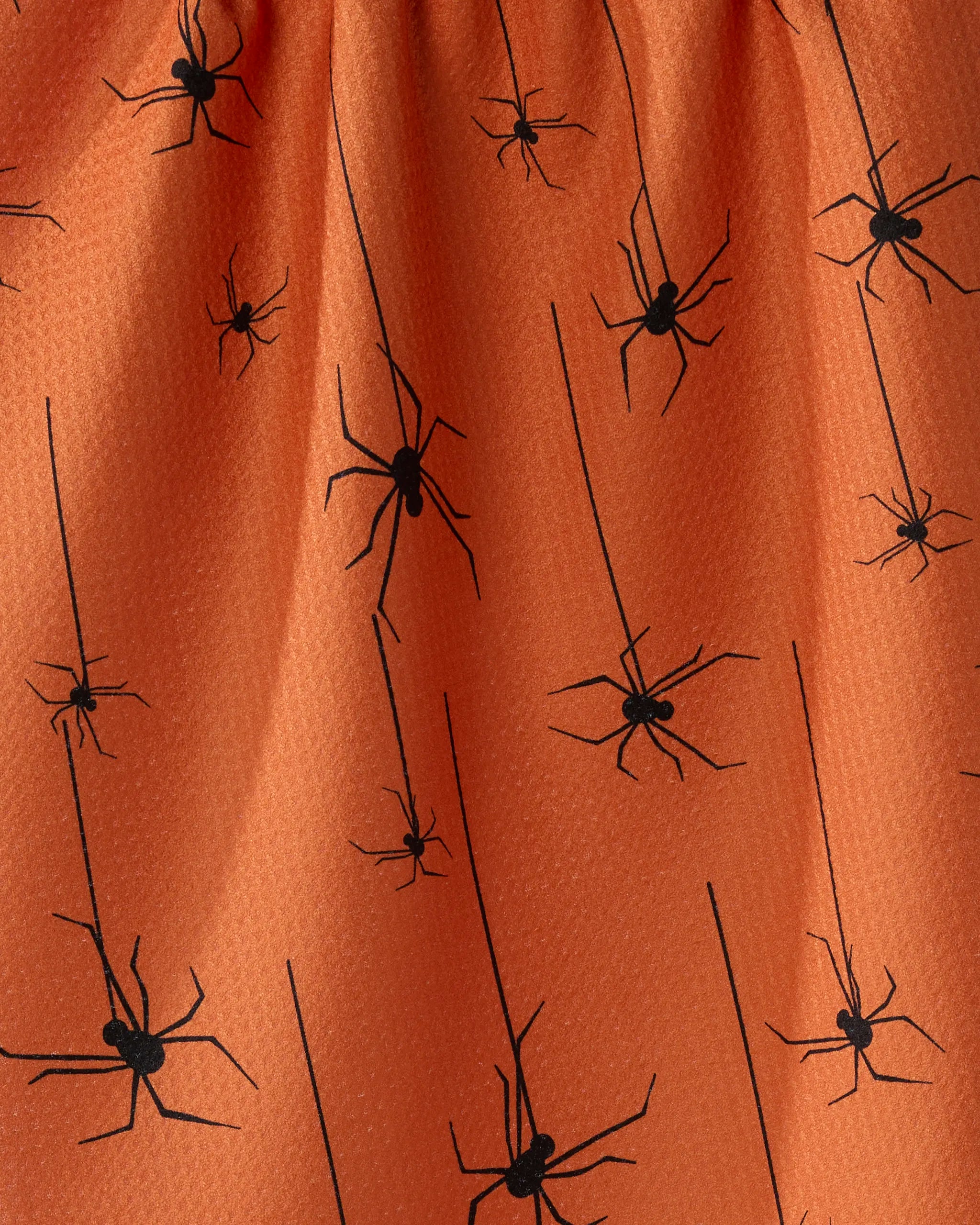 The Geometry Suspended towel features orange fabric with black spiders dangling from thin lines like webs. This quick-drying towel adds a playful, spooky vibe to your kitchen decor.