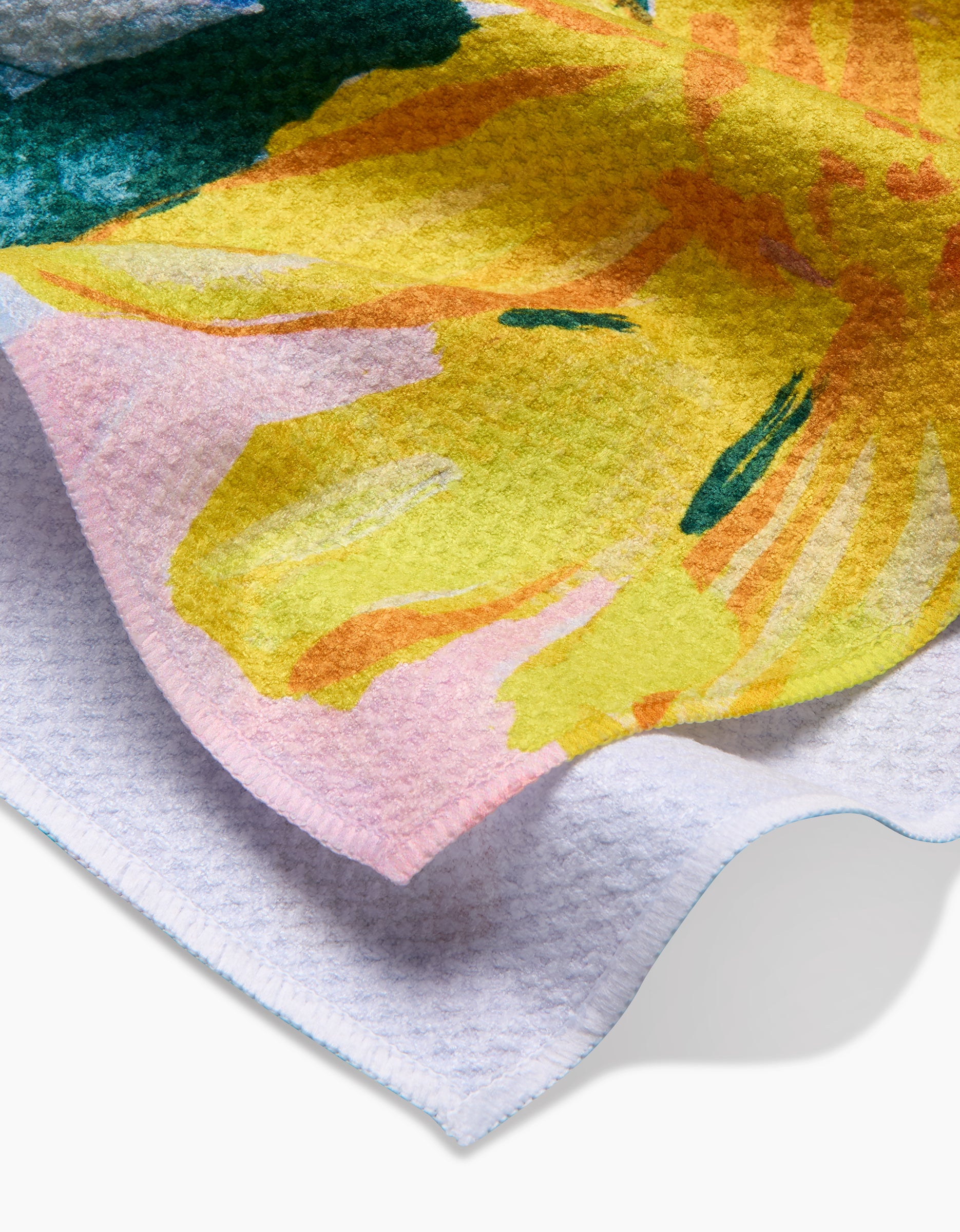 A close-up of the Suzzy tea towel by Ania Zwara Art, crafted from Geoweave fabric and showcasing a vibrant floral print with bold yellow and green petals on a soft pink and white background.