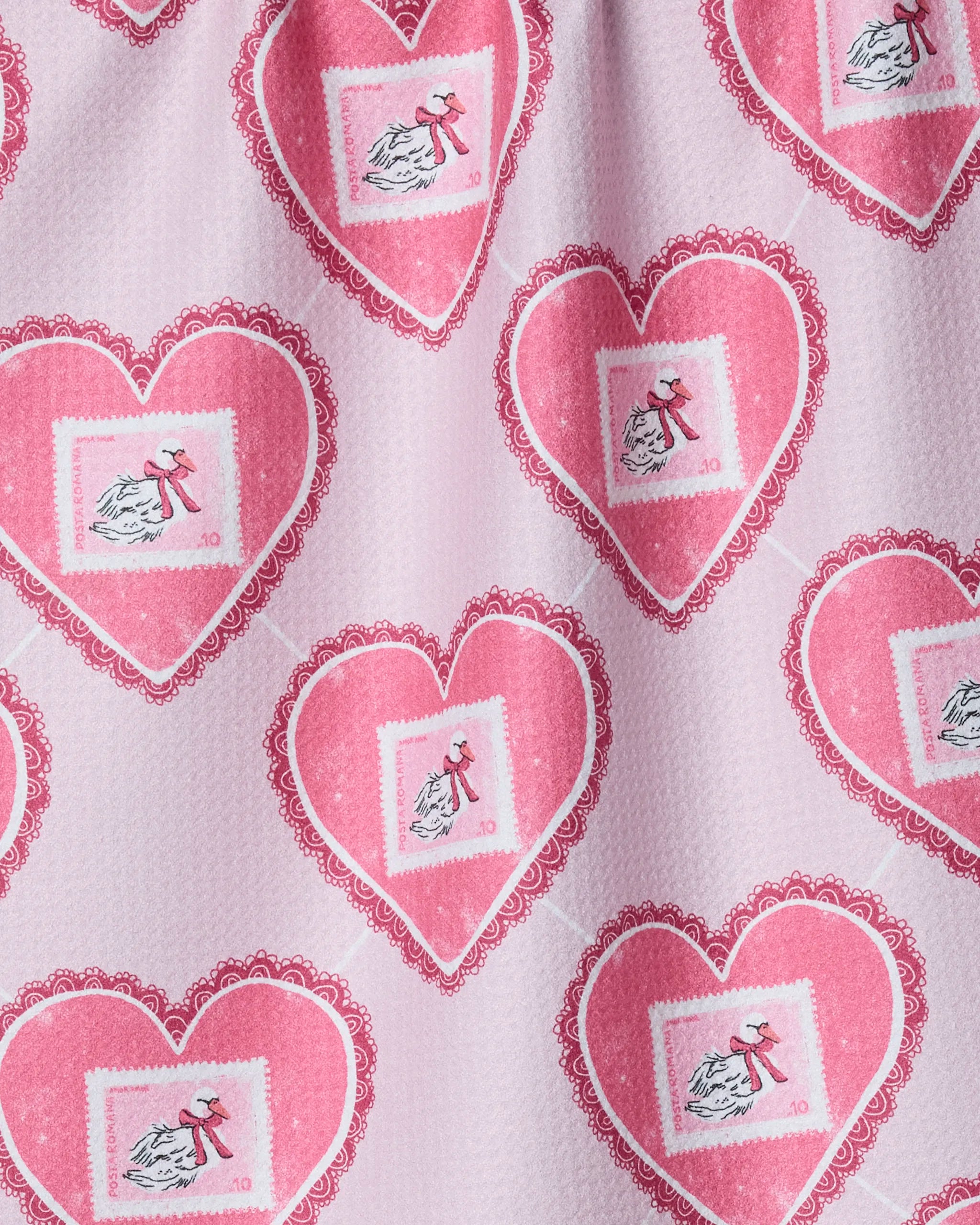 Swan Argyle by Geometry: A tea towel made from recycled materials, featuring a light pink, lightly textured background patterned with large red hearts holding white stork postage stamps.