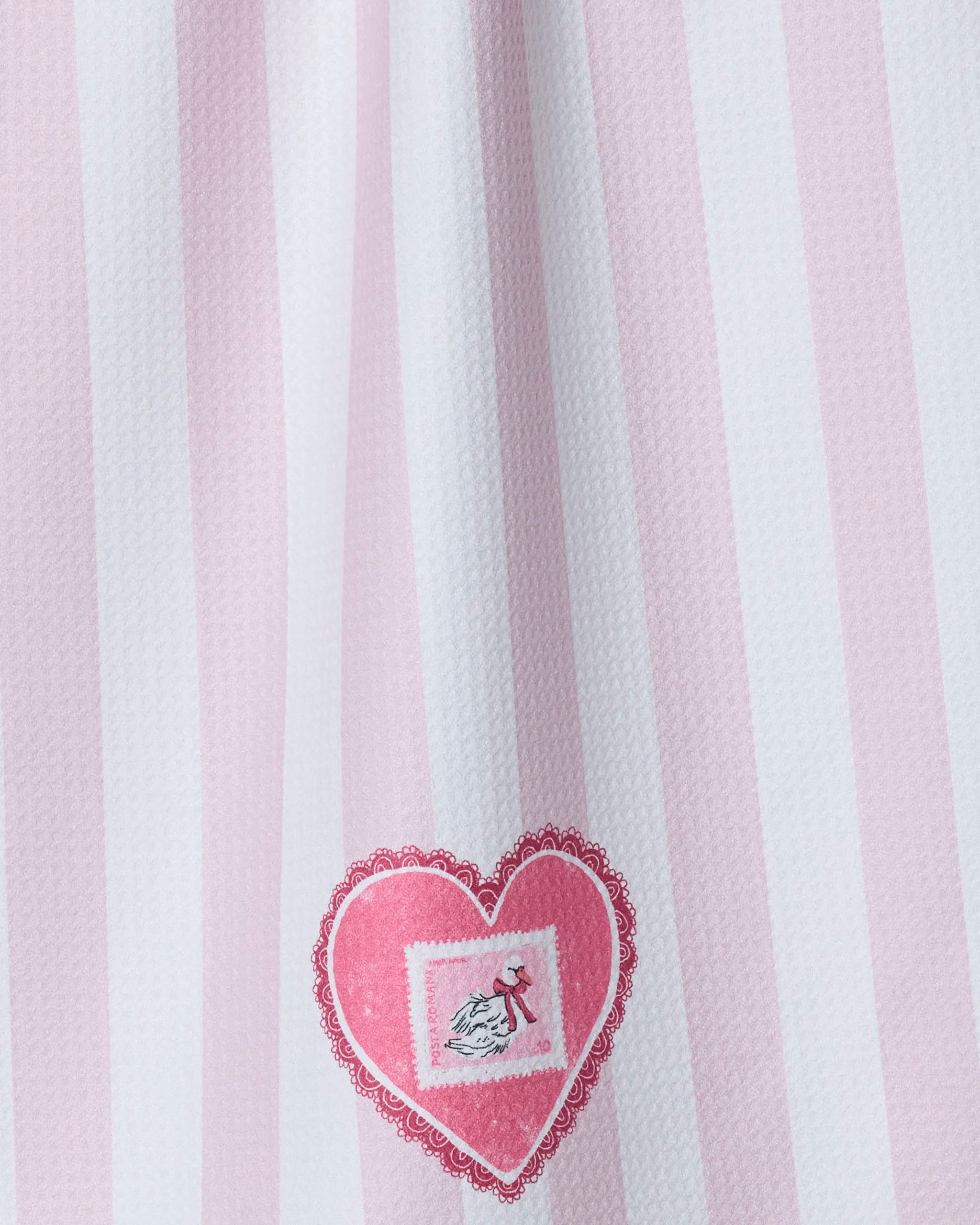 The Geometry Swan tea towel features pink and white vertical stripes, a heart-shaped pink design, and a charming bird illustration near the bottom. Made from recycled materials.