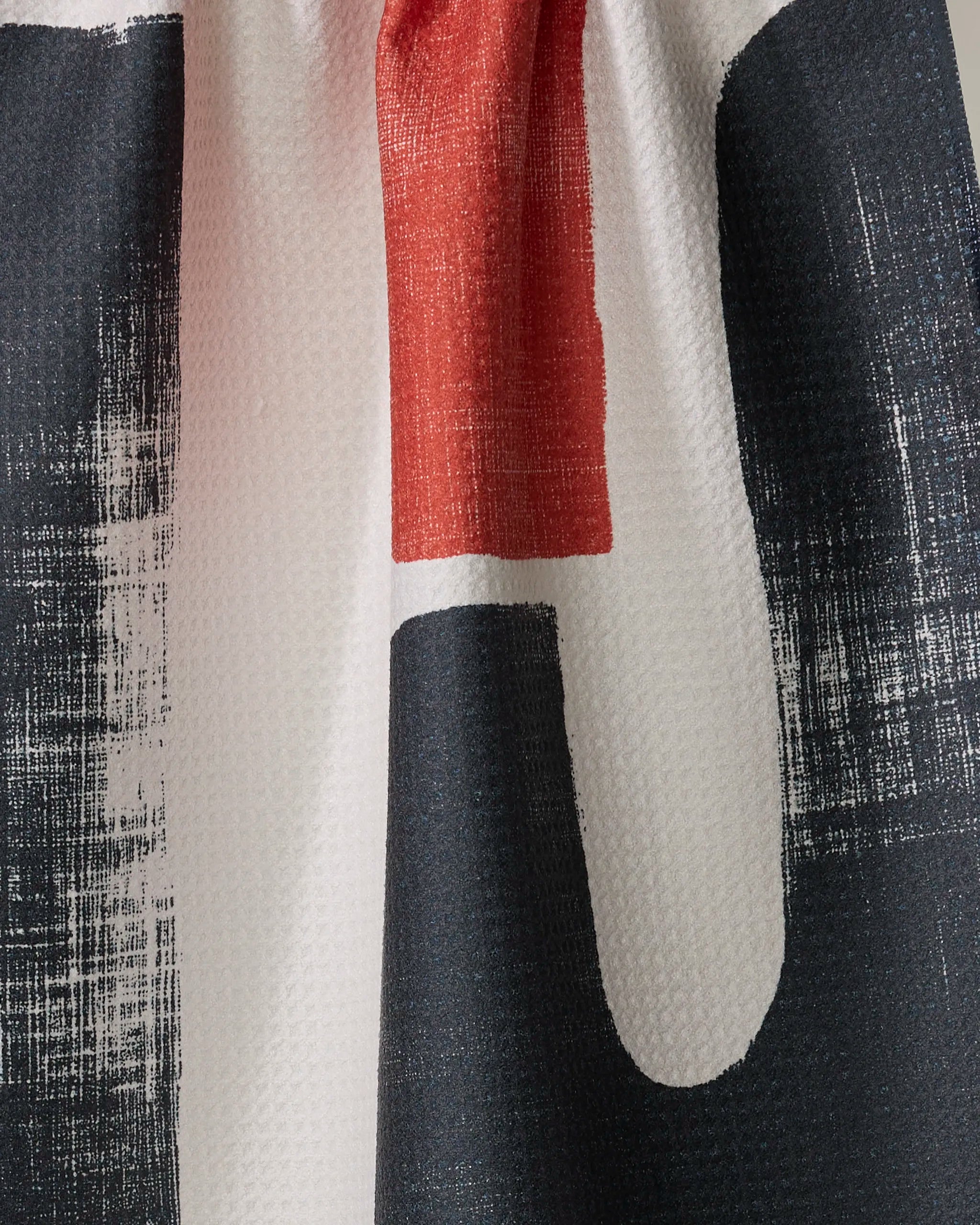 A close-up of the Geometry Sway tea towel, showcasing its textured surface and bold black, white, and red abstract vertical pattern, crafted from recycled materials.