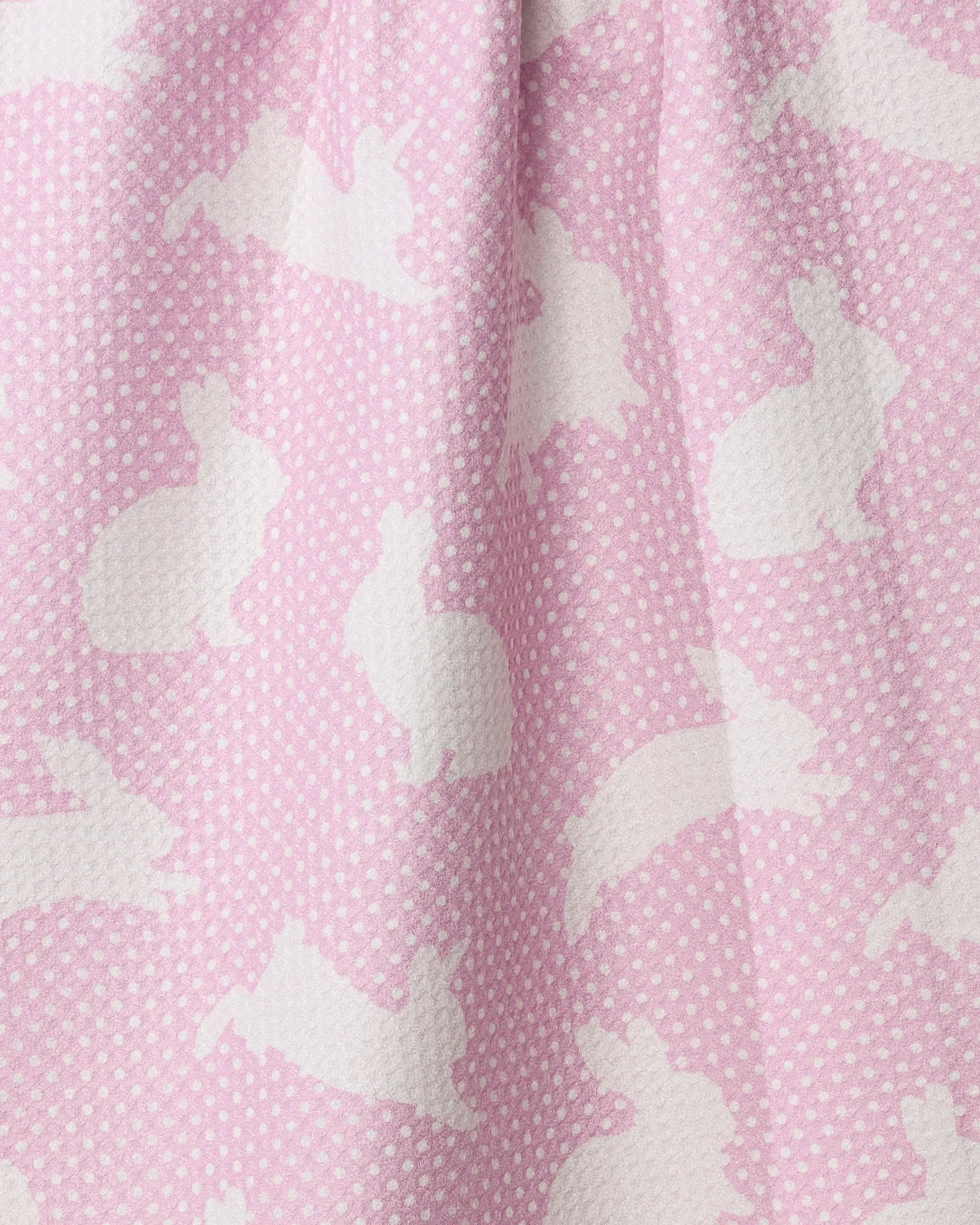 A close-up of Geometry's Sweet Bunny tea towel shows pink, quick-drying recycled fabric with white polka dots and rabbit silhouettes, draping softly in gentle folds.