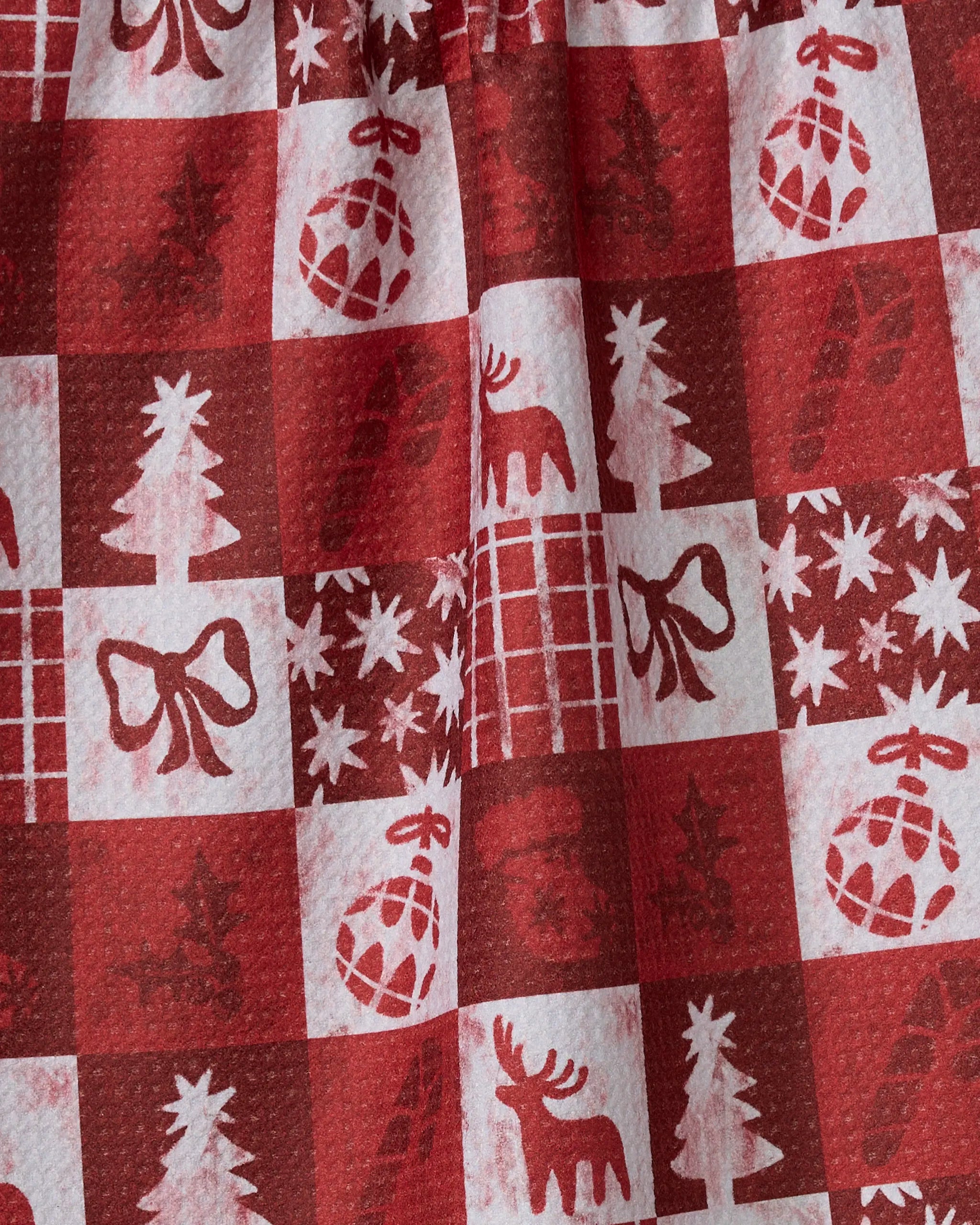 The Sweet Carol tea towel by Geometry features red and white festive patterns—Christmas trees, bows, ornaments, stars, reindeer, and gifts—in a repeating design. Made from quick-drying recycled materials for eco-friendly holiday cheer.