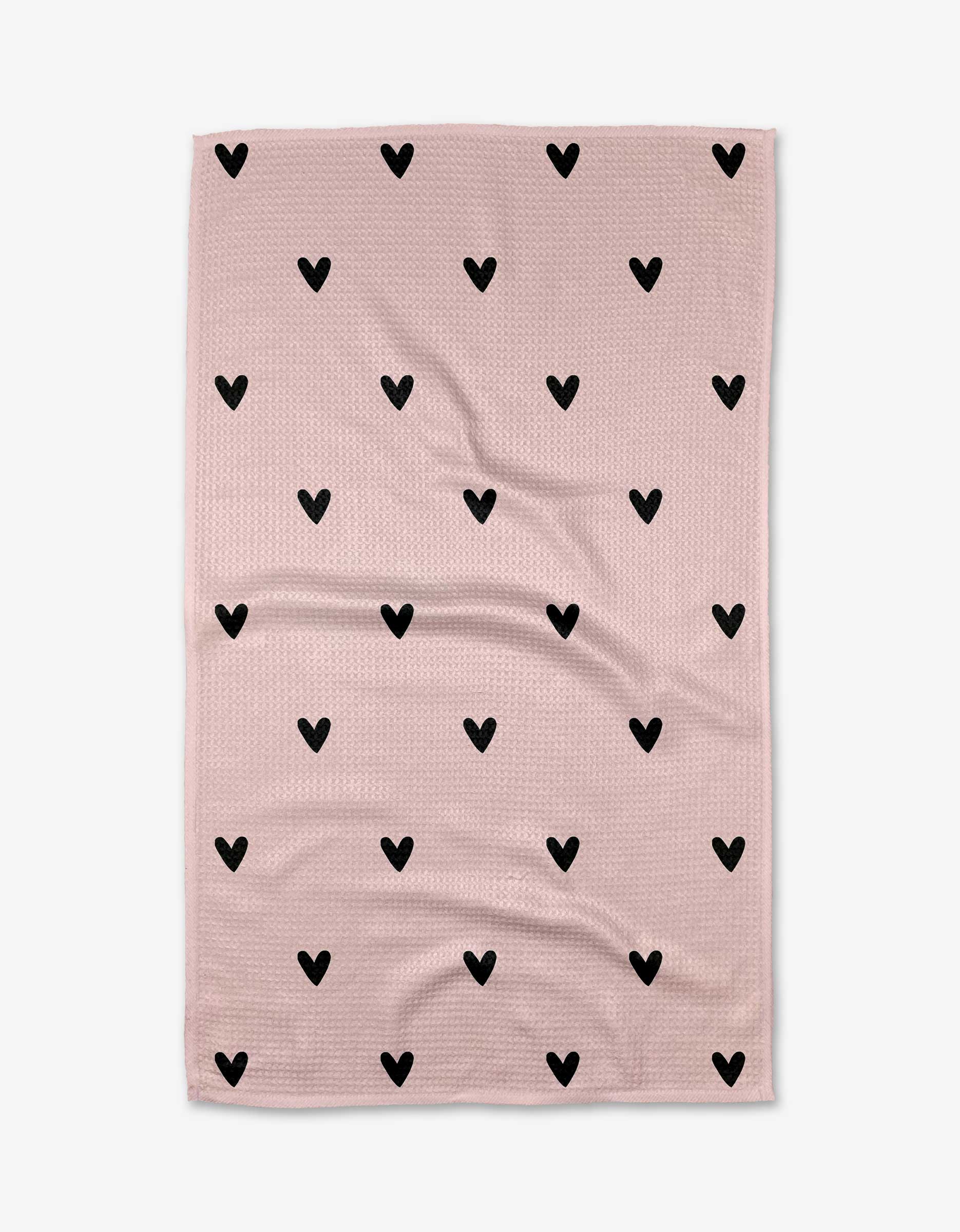 The Kailee Wright Sweet Hearts blanket features a light pink background with evenly spaced black hearts, made from ultra-absorbent Geoweave fabric and shown laid flat with slight wrinkles.
