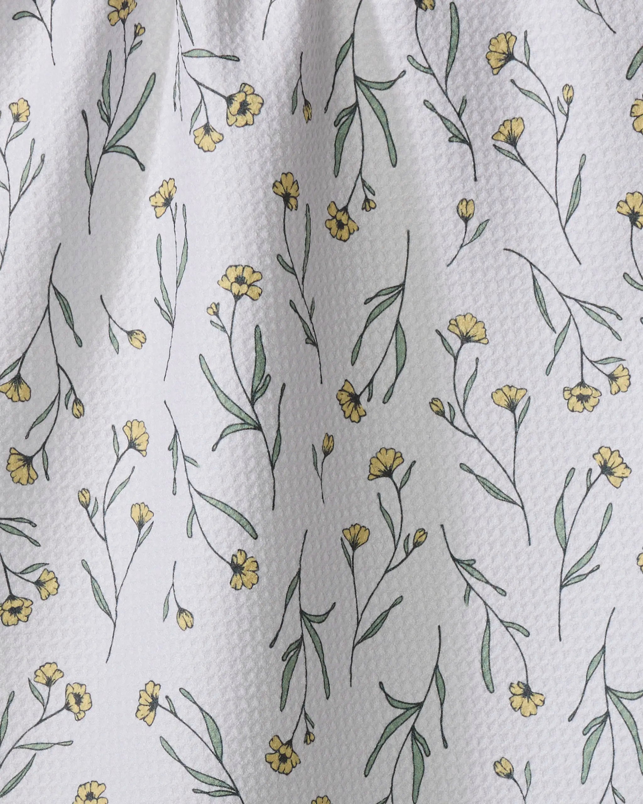 The Sweet Little Nothings dish towel by Ashley Celena features absorbent white textured fabric adorned with small yellow flowers and green stems, adding a charming touch to any kitchen.
