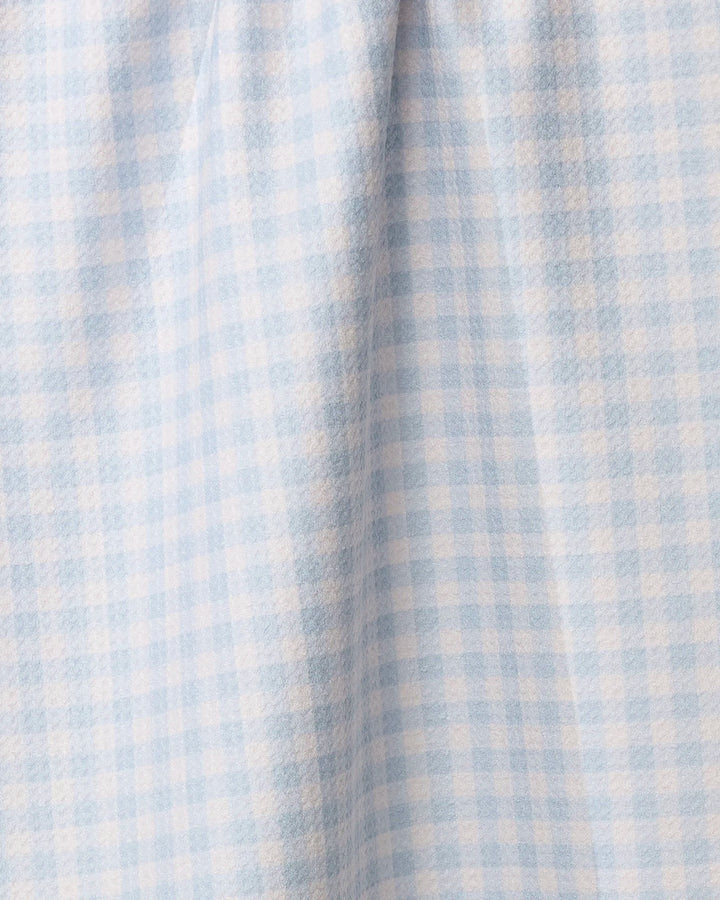 A close-up of the Sweet McKelle kitchen towel by Geometry shows its soft, light blue and white gingham checkered pattern with gentle folds and delicate shadows.
