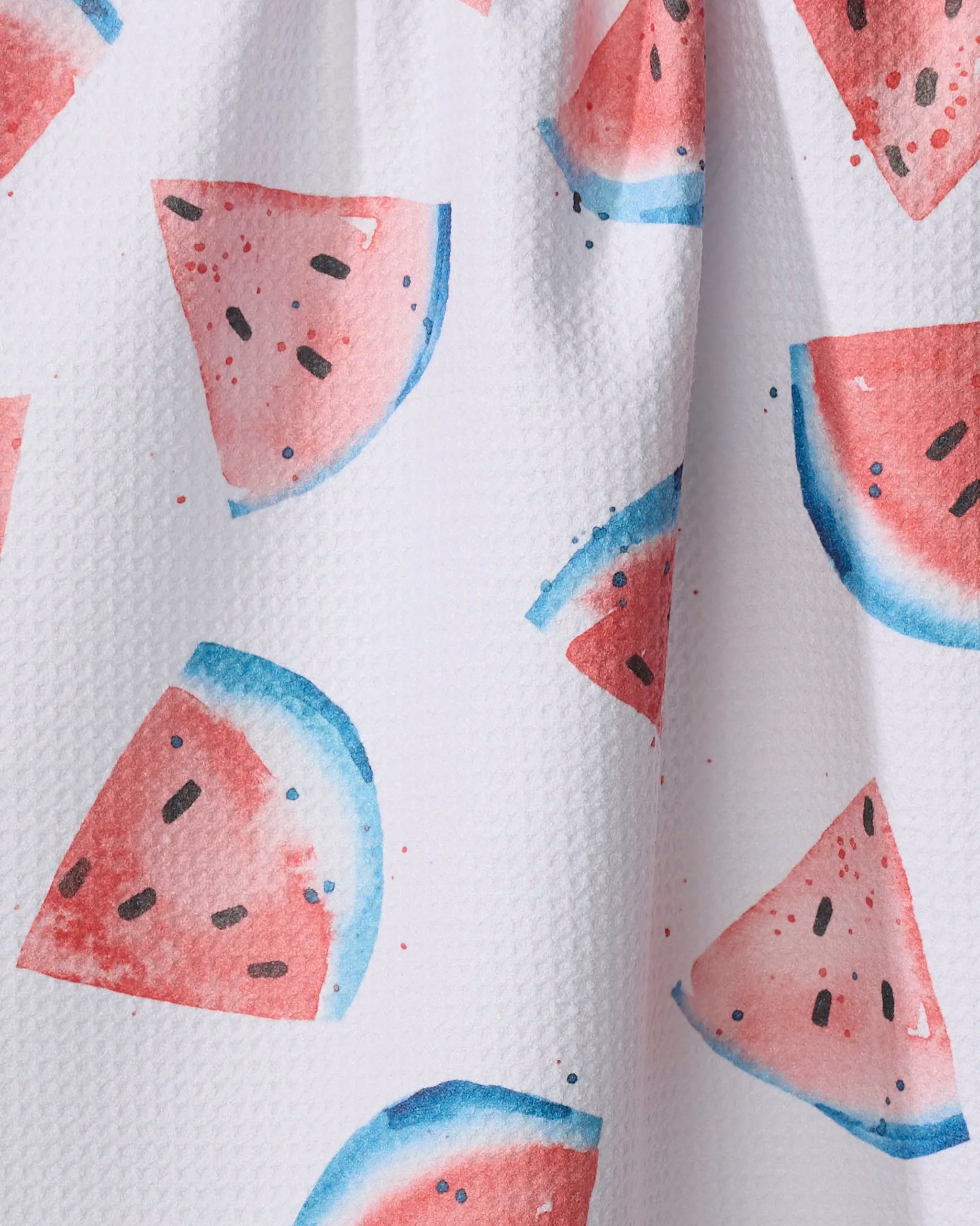Close-up of Sara Mari’s Sweet Slice Of July eco-friendly tea towel, featuring a white textured background with watercolor-style watermelon slices—pink-red fruit, black seeds, and blue-green rinds.