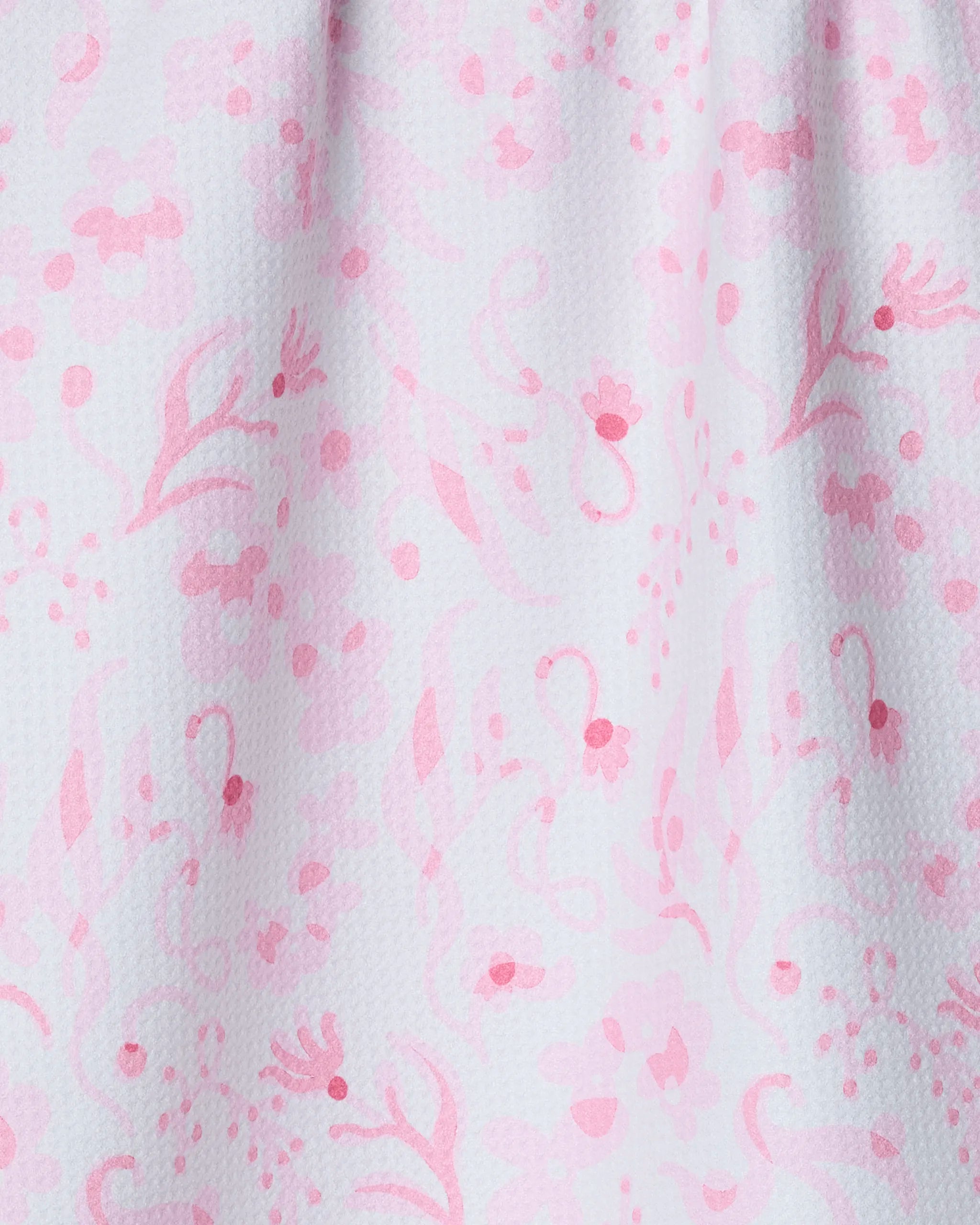 The Sweets and Florals tea towel by Geometry features a light pink floral pattern with flowers, leaves, and swirls on textured white. Made from quick-drying recycled materials, its fabric drapes softly with delicate folds.