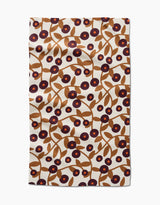 The Lizzie Clark Swirling Vines tea towel is rectangular, made from recycled materials, and features brown branches with leaves and purple and red circular flowers on a cream background.
