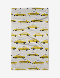 Taxi Cabs tea towel by Vaishali Design Studio: an ultra-absorbent white cloth with a neat horizontal pattern of yellow taxis featuring black wheels and TAXI on the side.