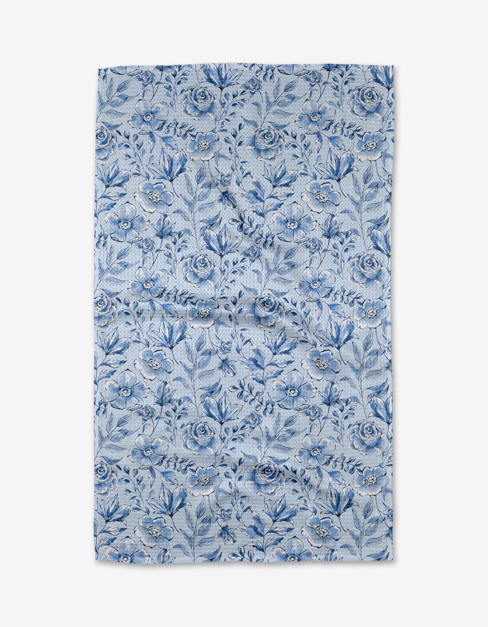 The “Tea Set Blossoms” kitchen towel by Sara Mari is a rectangular, recycled piece featuring a blue floral pattern with assorted flowers and leaves on a light background, shown laid flat against a white surface.