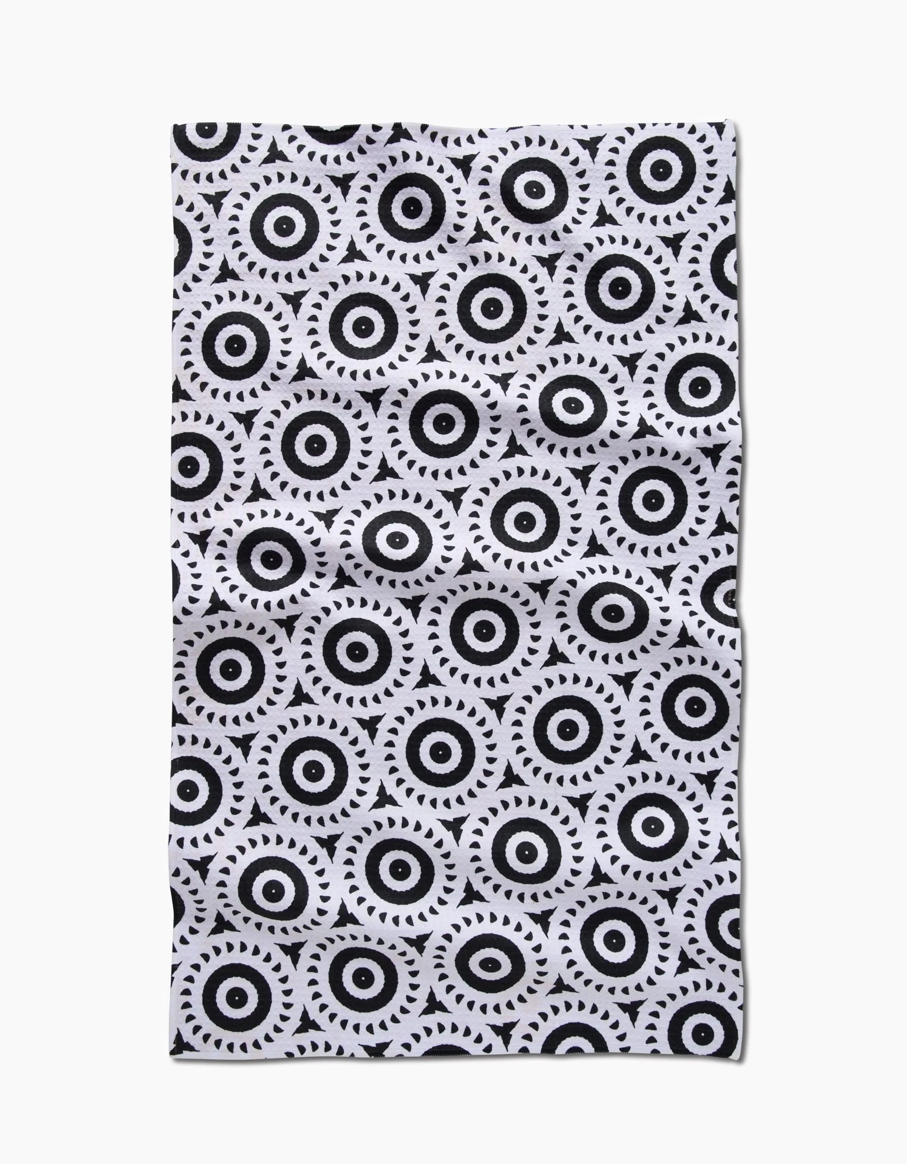 The Texas Two Step by Katherine Berkeley is a rectangular tea towel with repeating concentric black circles and small triangles on a white Geoweave fabric, which has a slightly wrinkled appearance.