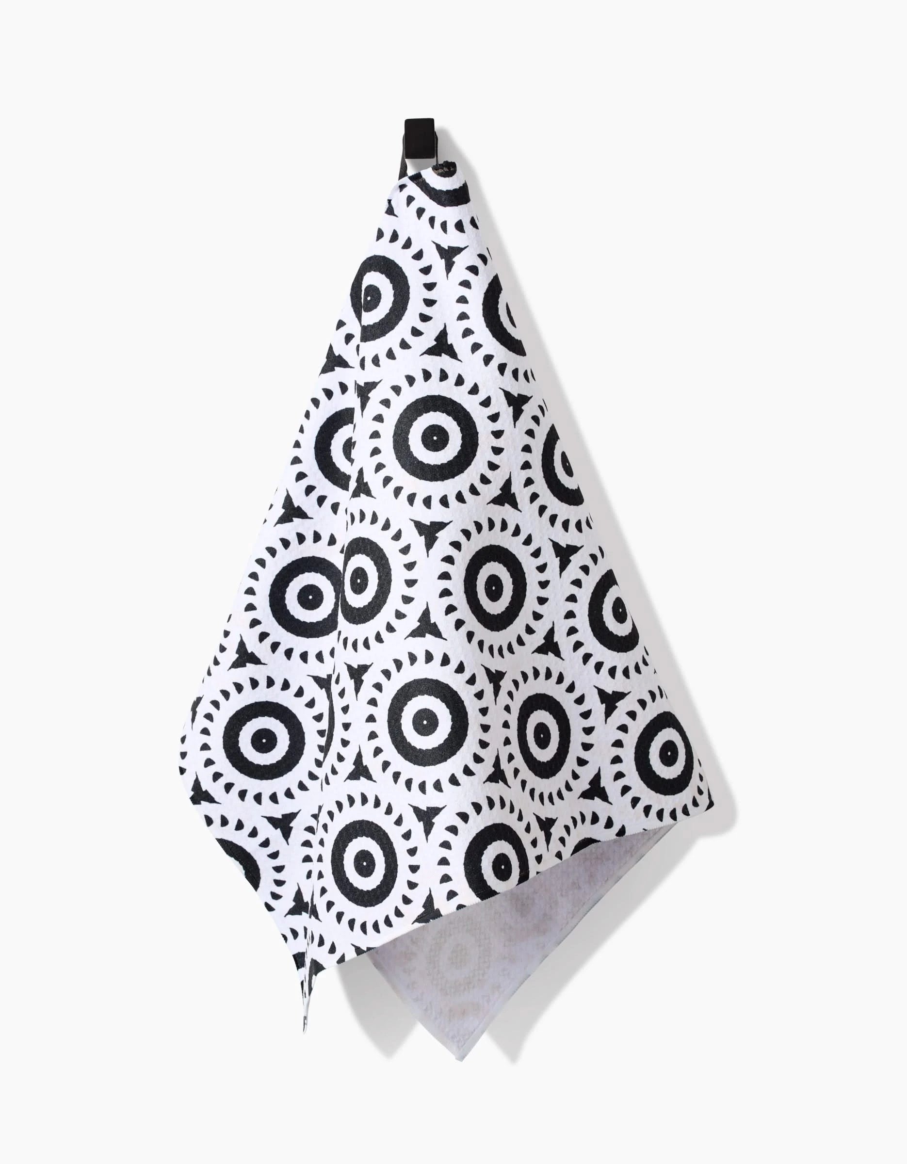 The Texas Two Step Tea Towel by Katherine Berkeley features black circular geometric patterns on white recycled fabric, finished with a black hanging loop, shown against a plain white background.
